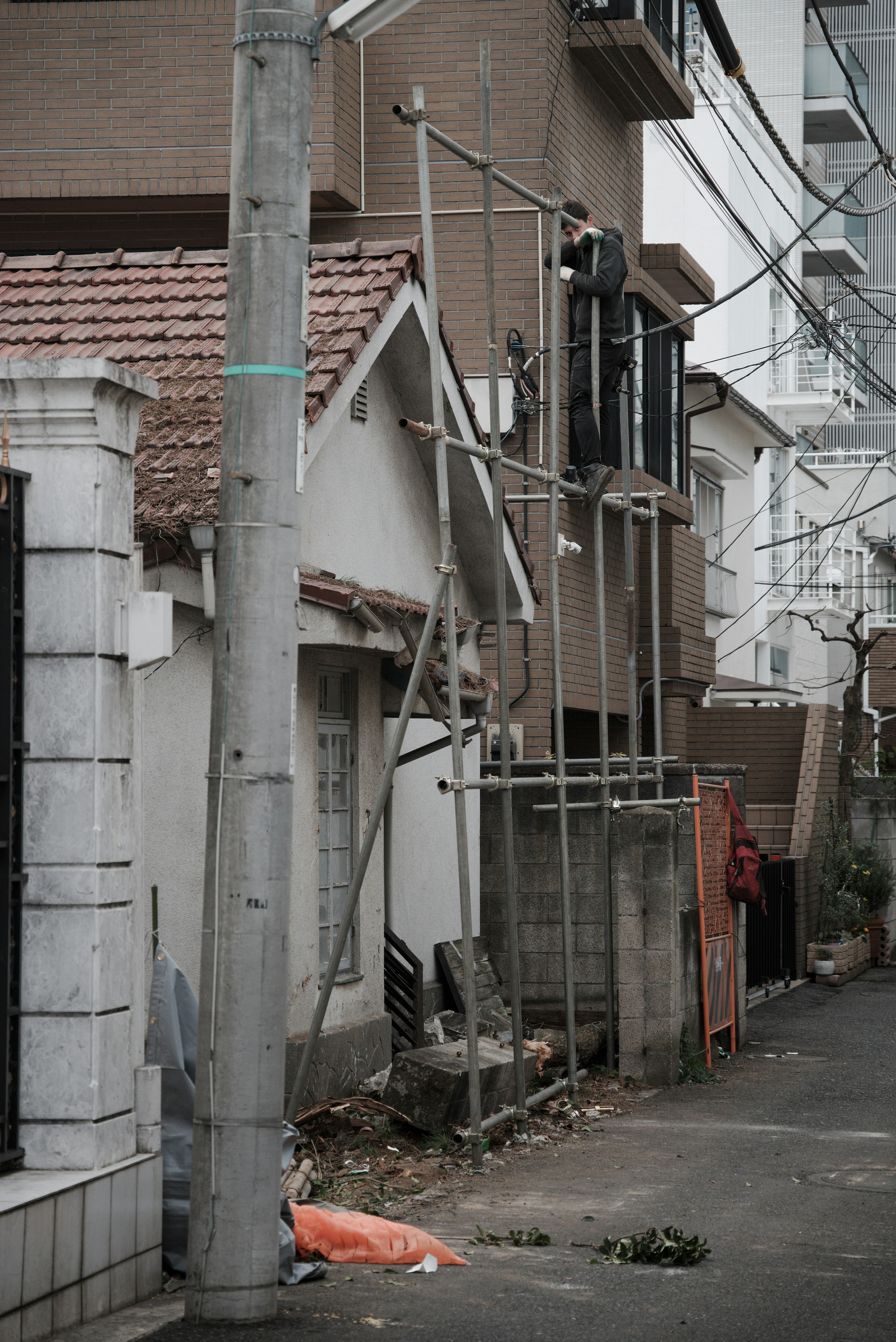 狭い路地に建設用足場が立てられた古い家の外観