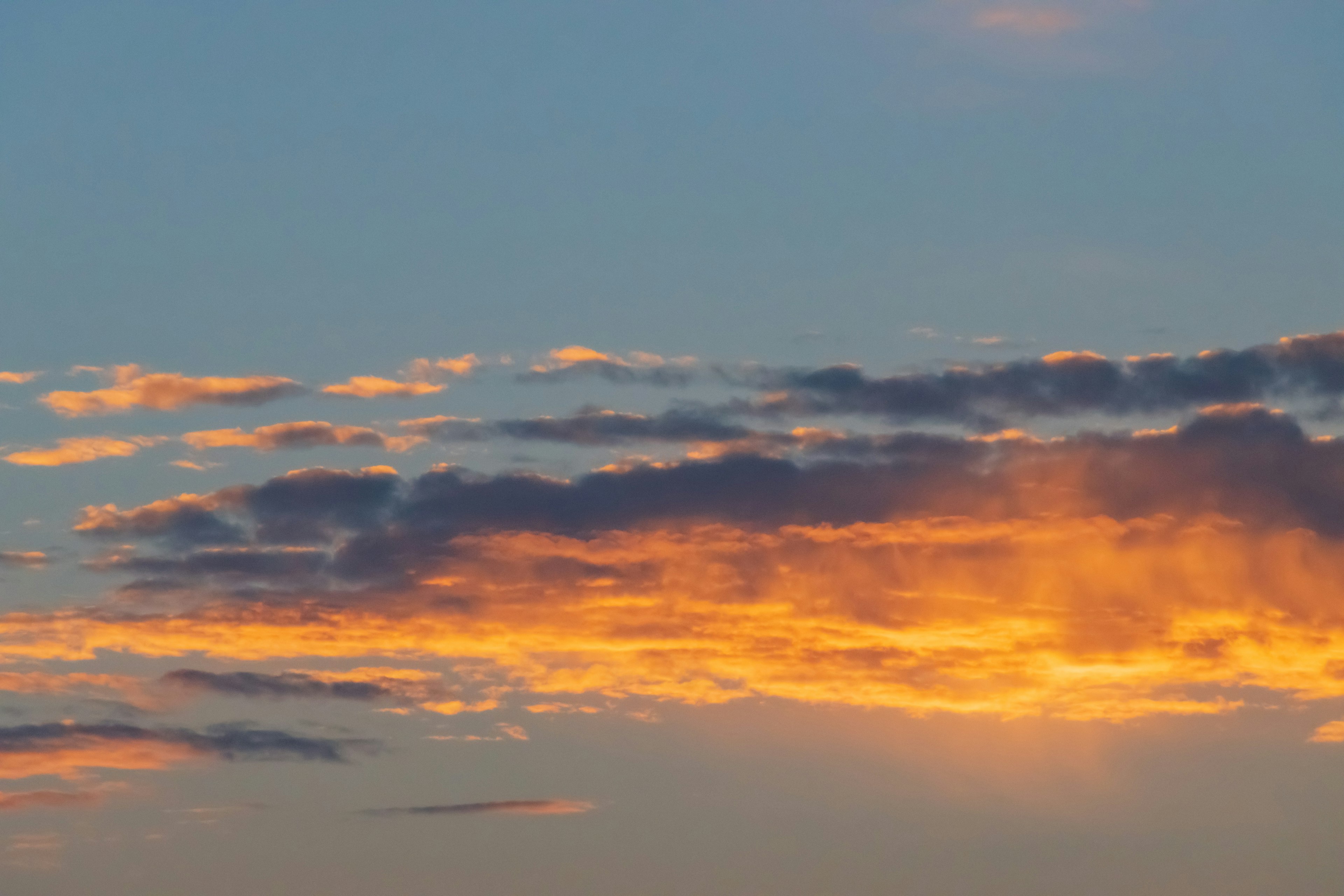 Lebendiger orangefarbener Sonnenuntergang mit Wolken vor einem blauen Himmel