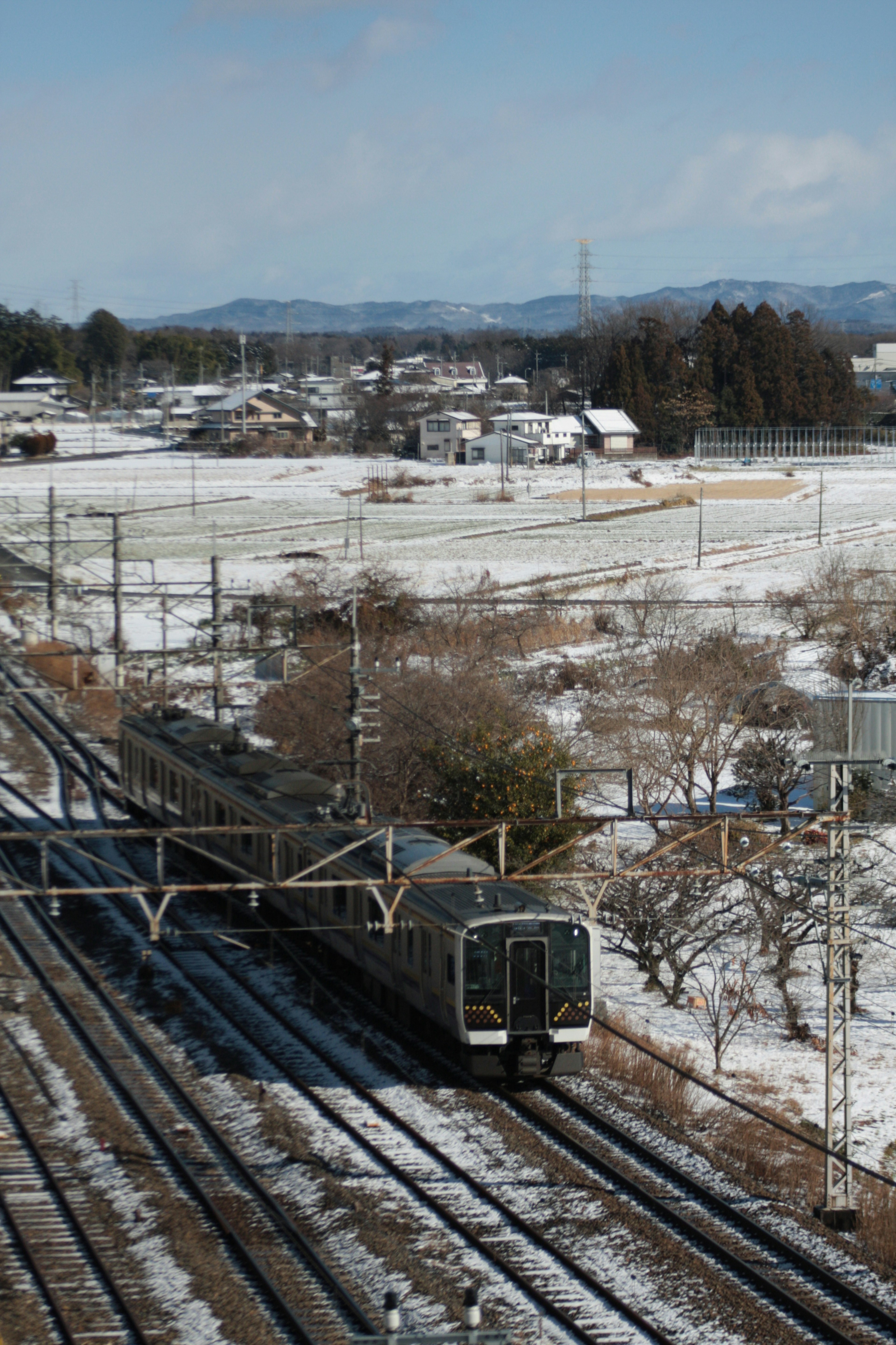 รถไฟวิ่งผ่านภูมิทัศน์ที่มีหิมะและรางรถไฟ