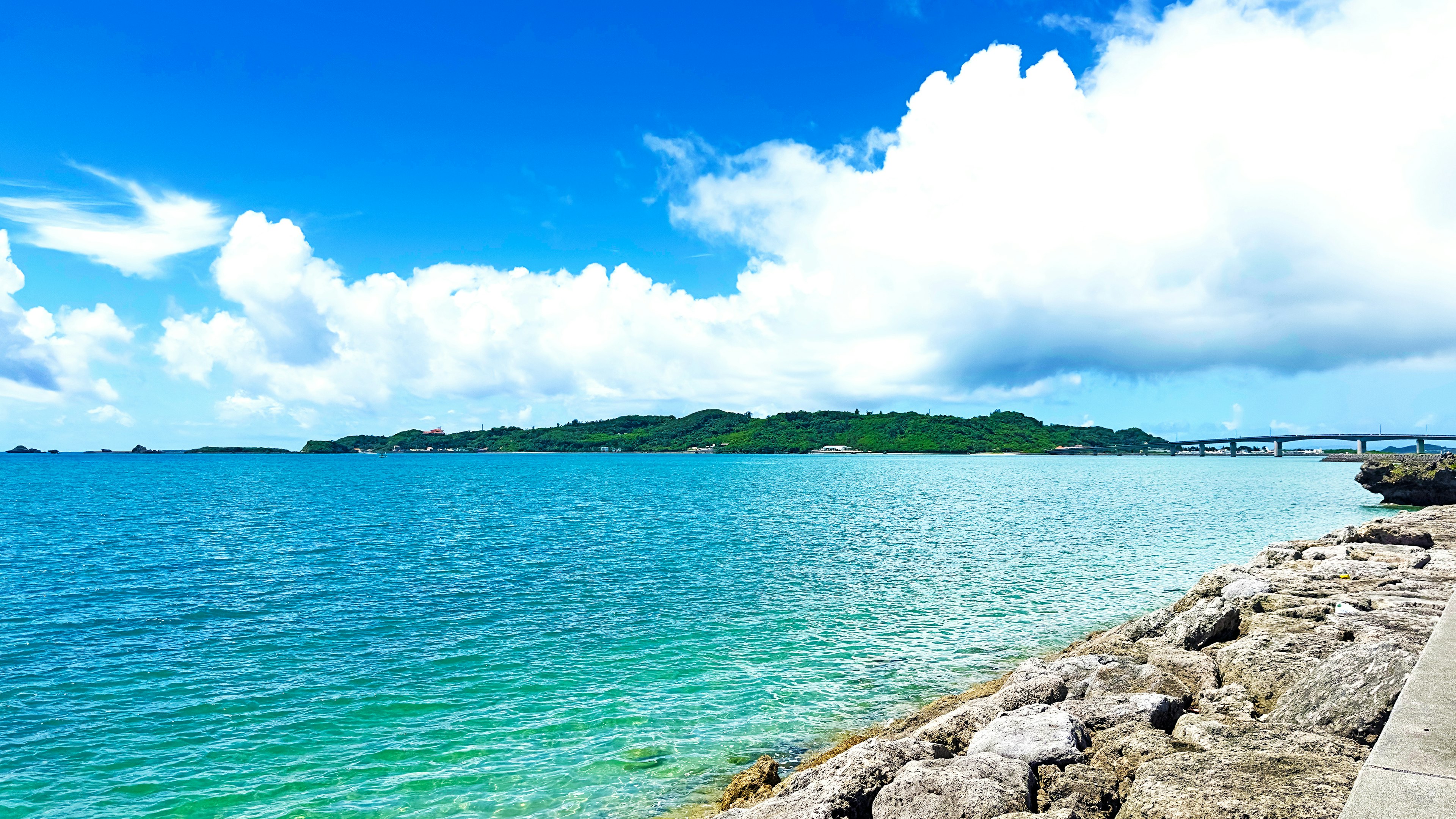 Vista panoramica dell'oceano blu e delle nuvole bianche riva rocciosa con un'isola verde