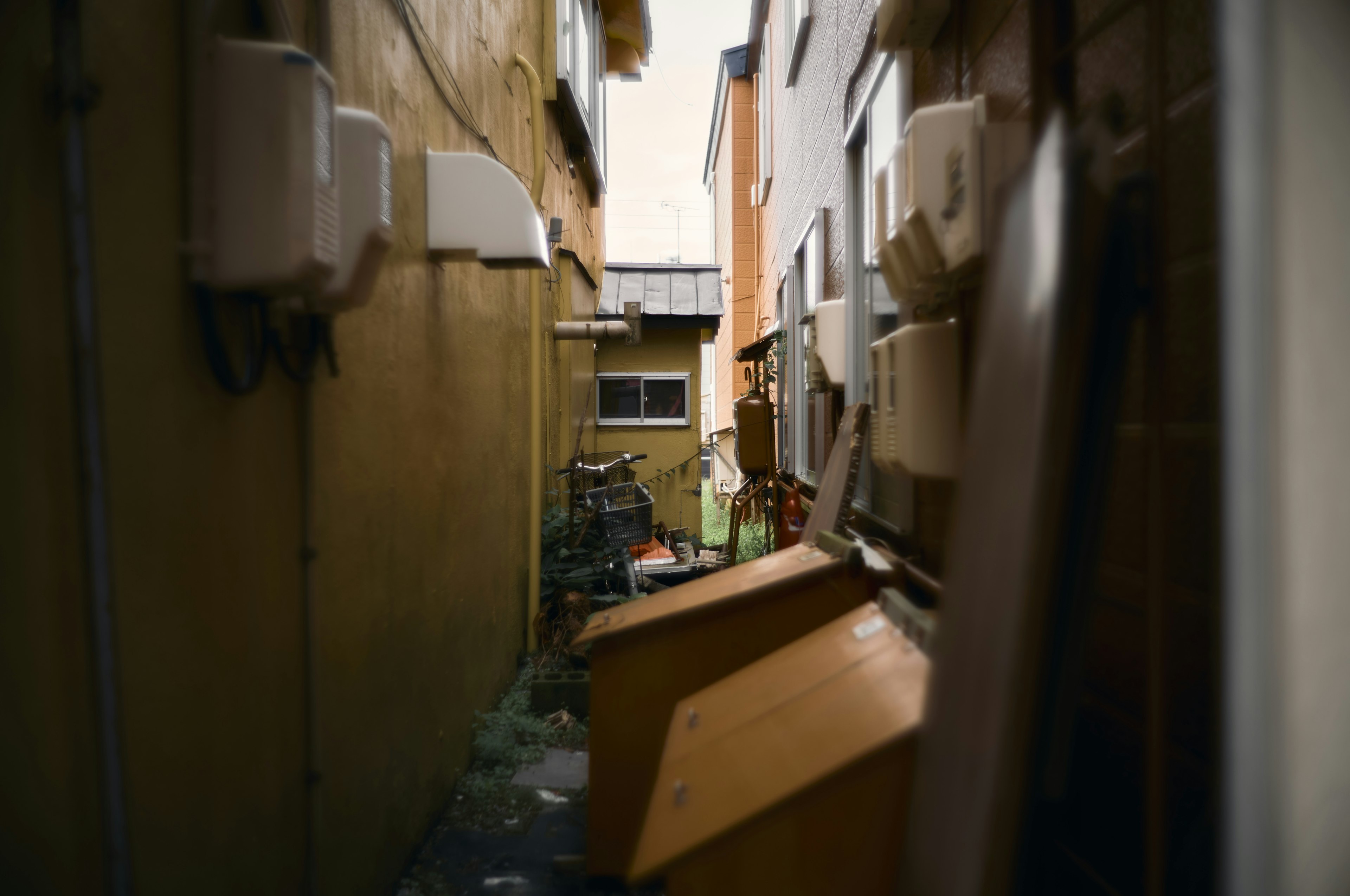 Callejón estrecho con cubos de basura amarillos y paredes de edificios