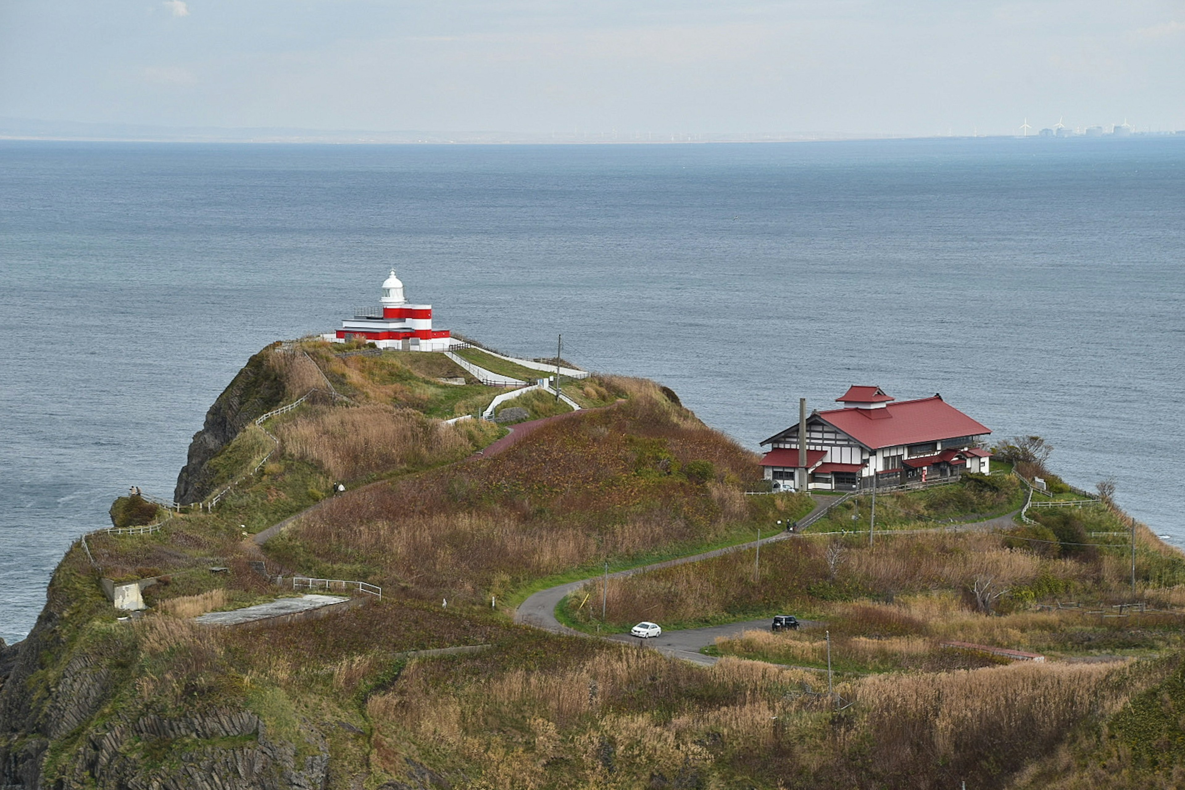 Vue panoramique d'un phare rouge et d'une maison sur une falaise côtière