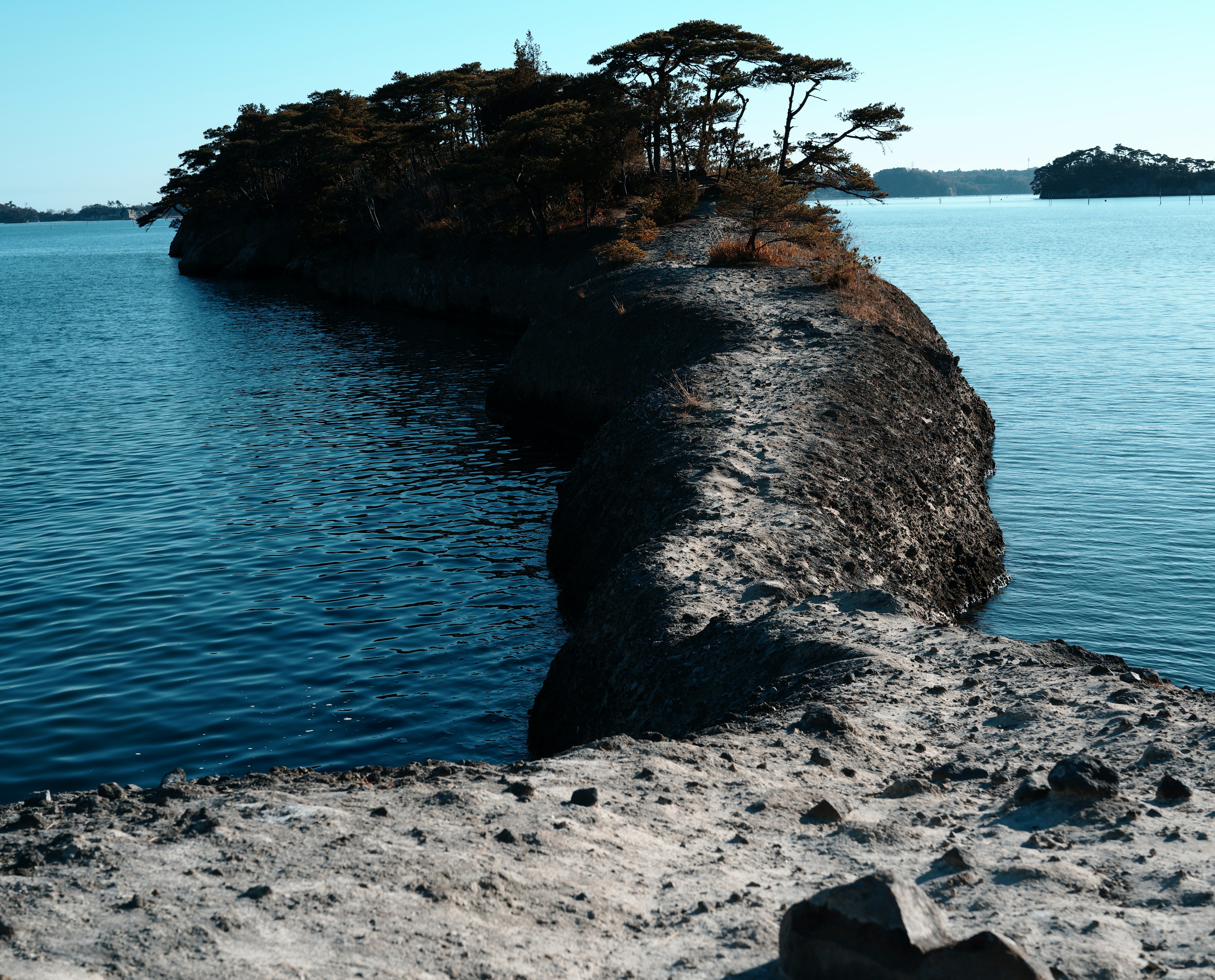 Ein Sandweg, der zu einer kleinen Insel umgeben von blauem Wasser führt