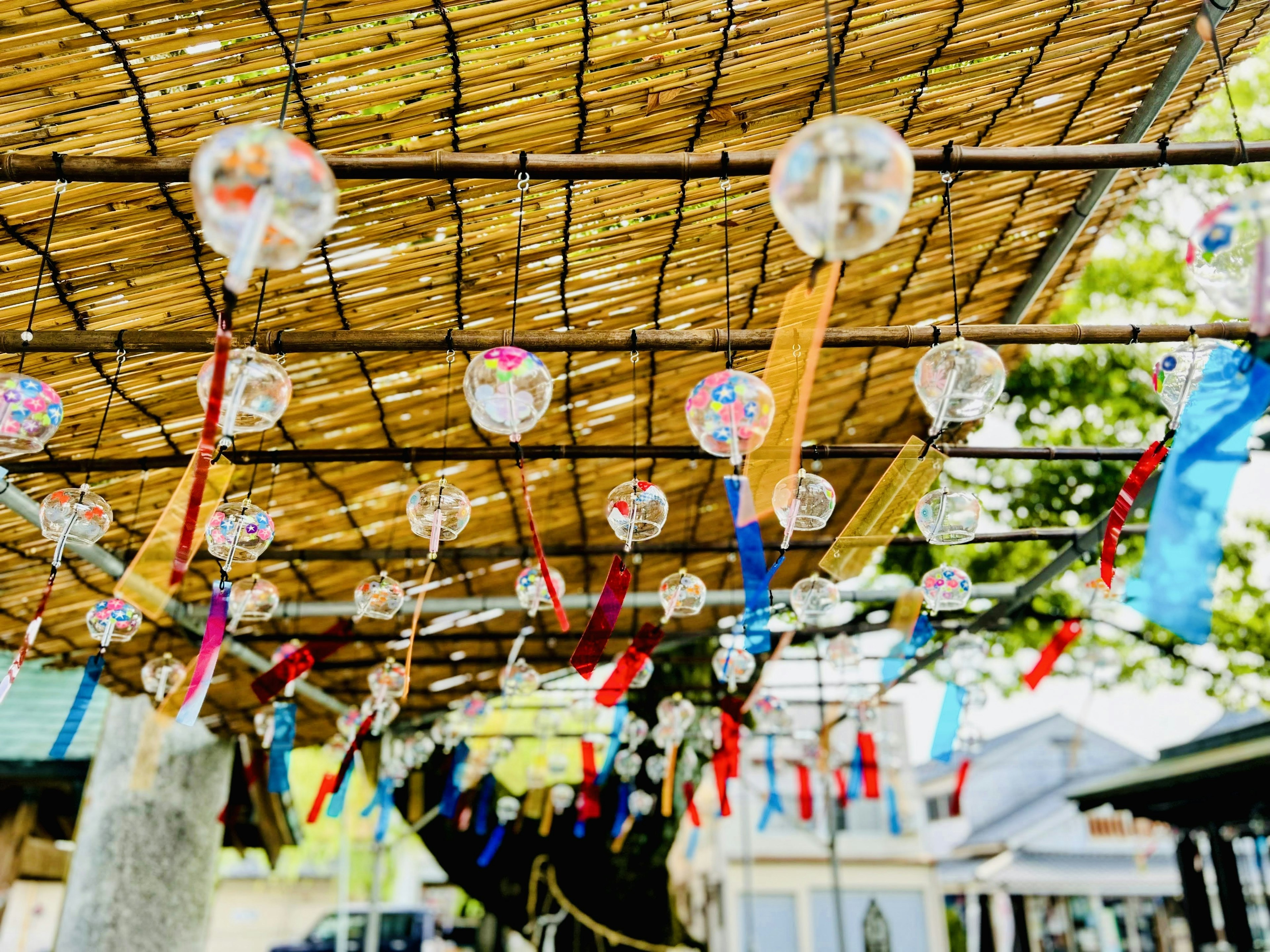 Wind chimes and colorful ribbons hanging under a bamboo roof