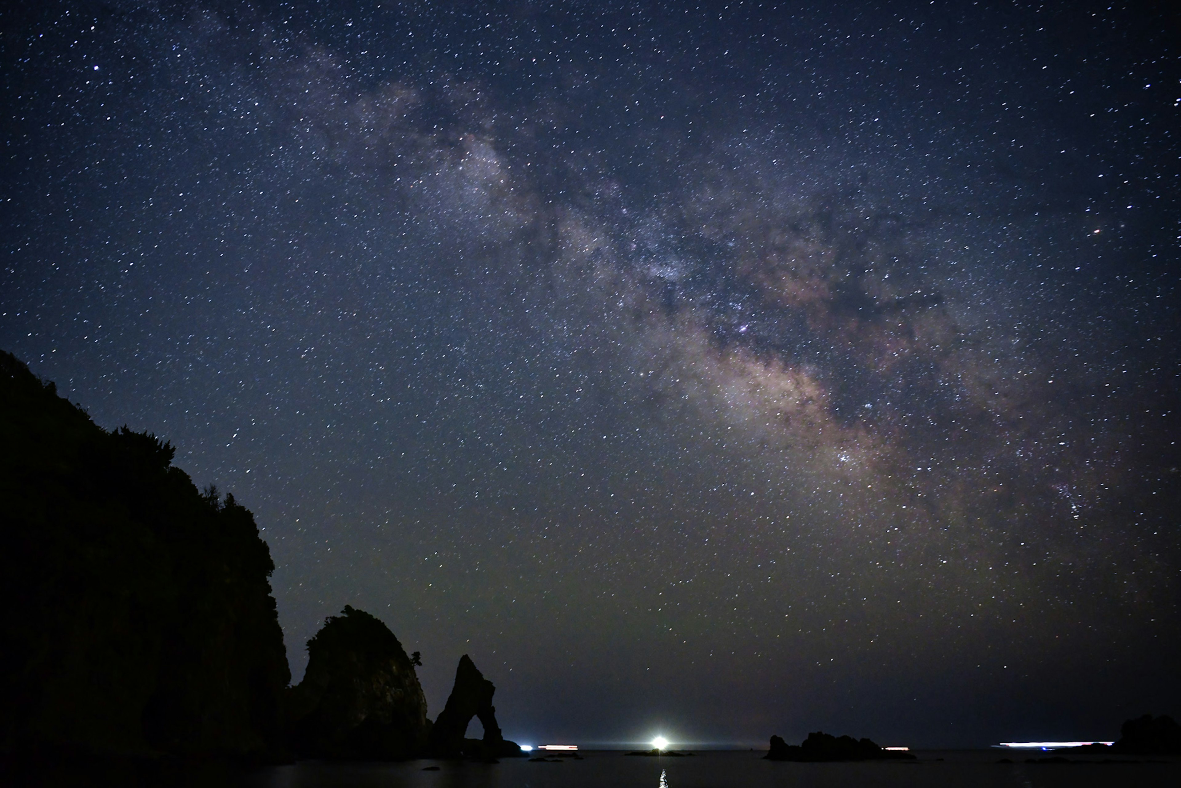 Vue imprenable de la galaxie s'étendant dans le ciel nocturne Rochers côtiers en silhouette contre les étoiles