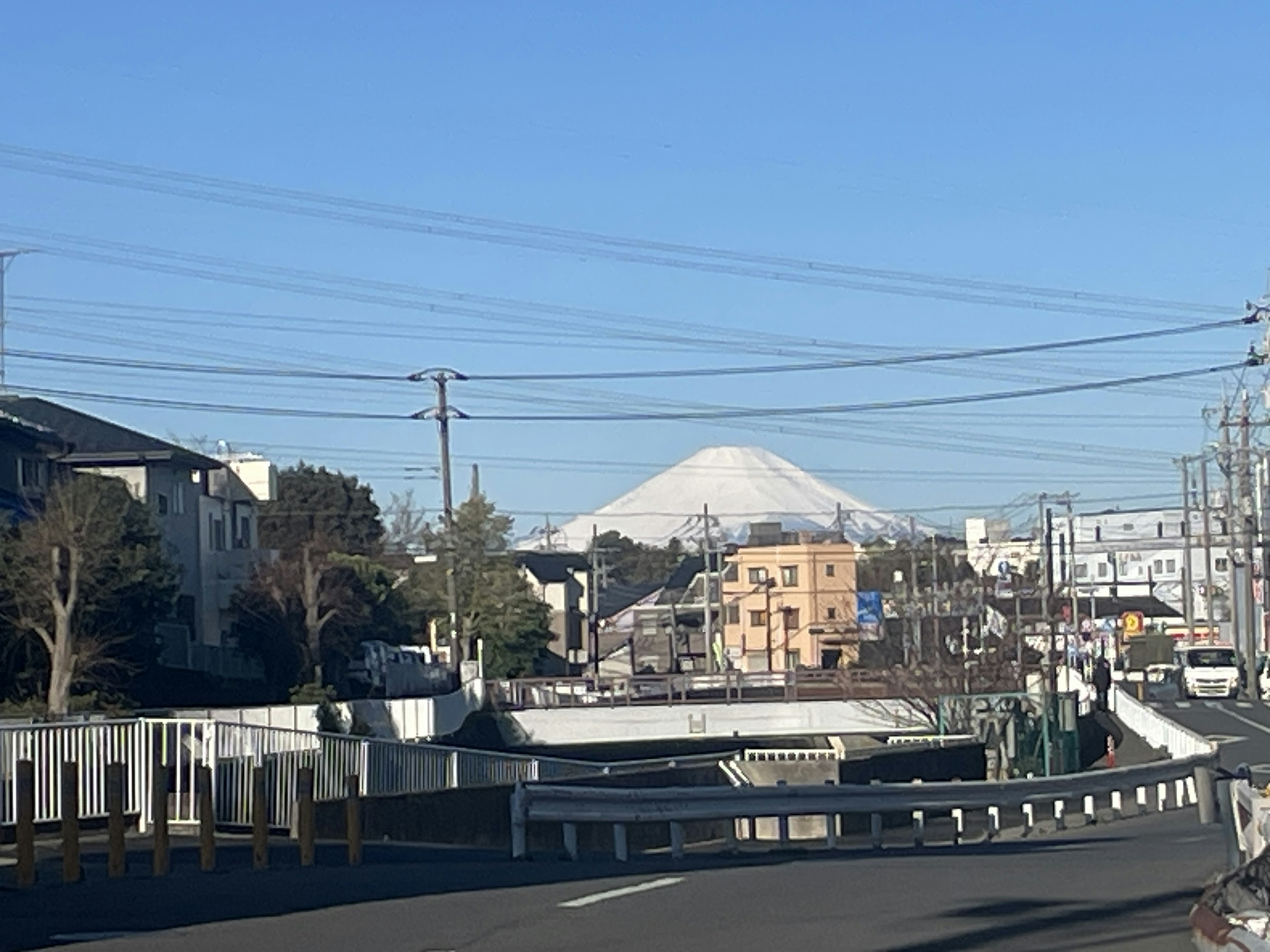 在晴朗的蓝天下，城市风景中可见雪覆盖的富士山