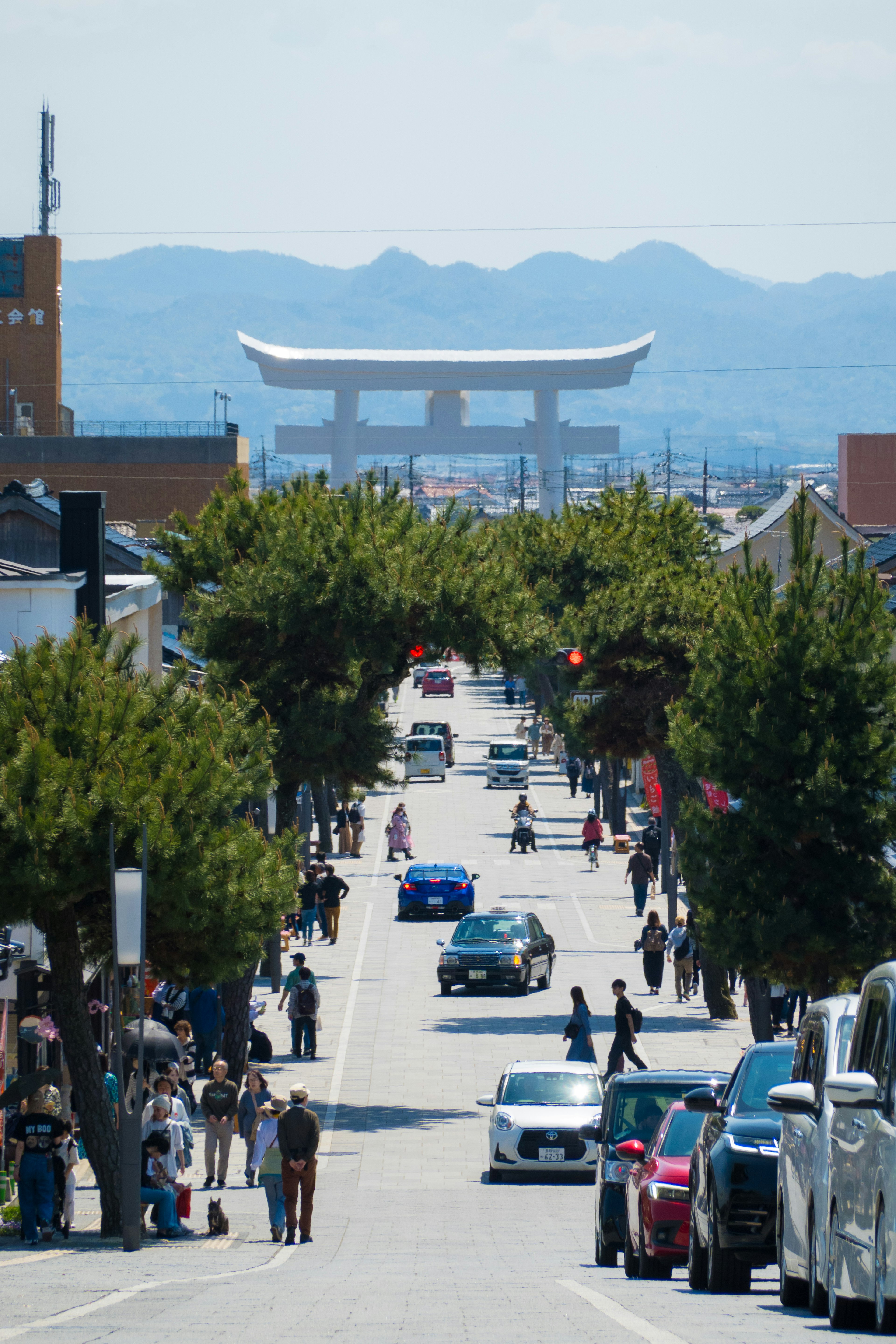 A street scene with a large torii gate in the distance under a clear blue sky