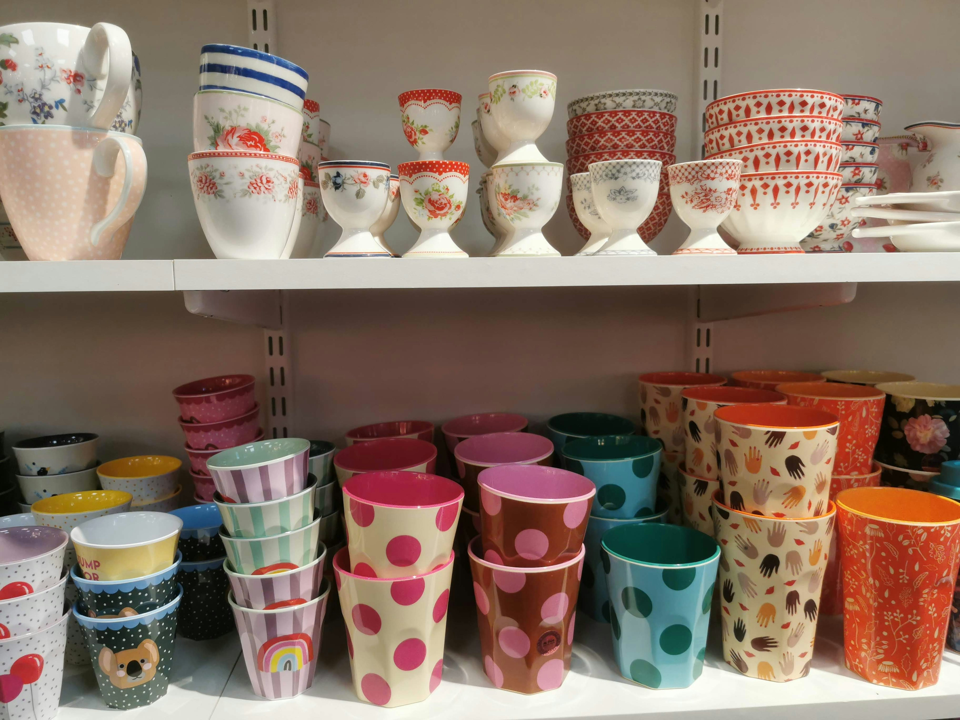 A shelf displaying a variety of colorful cups and bowls