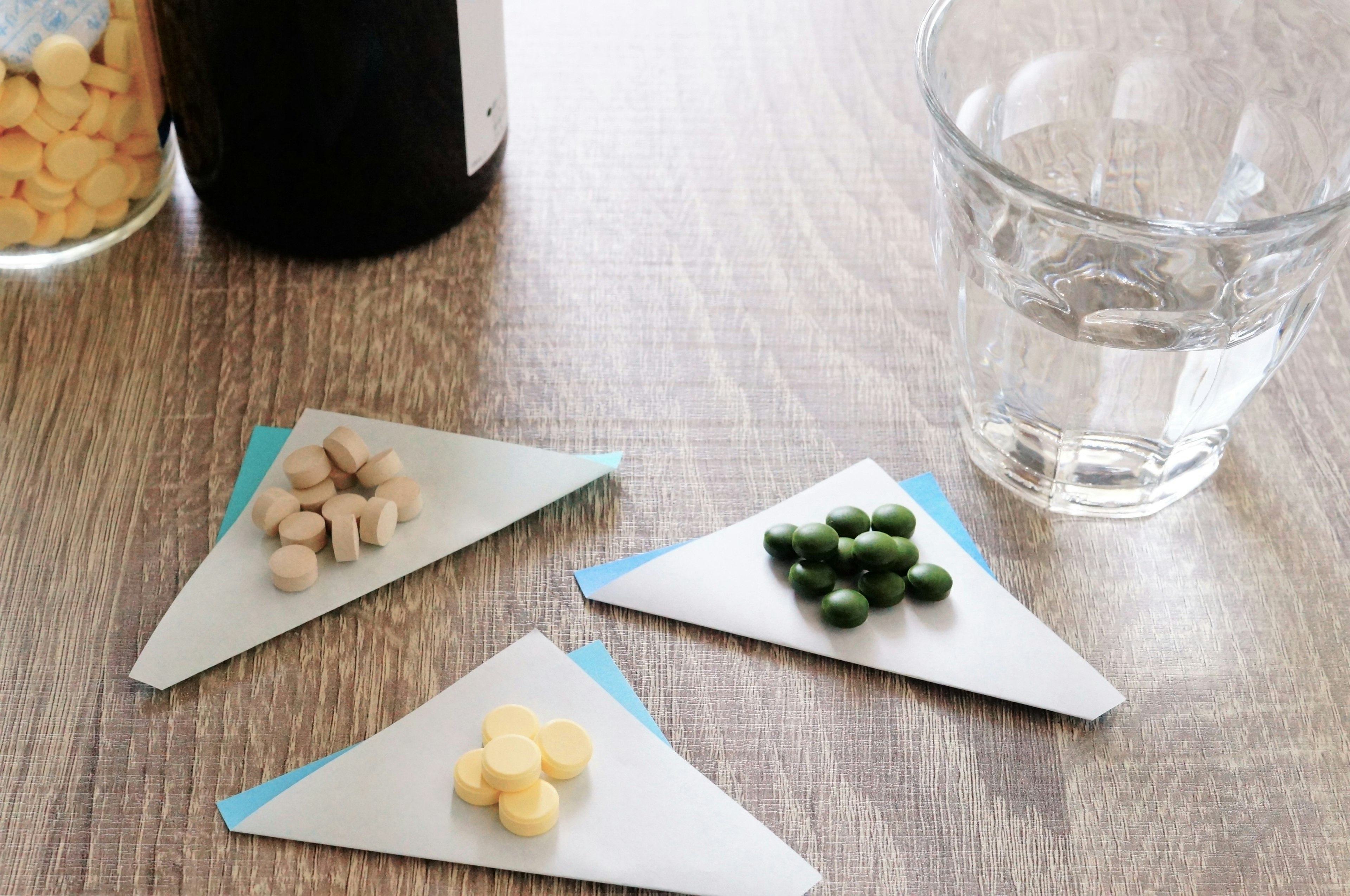 Different colored pills on triangular plates with a glass of water