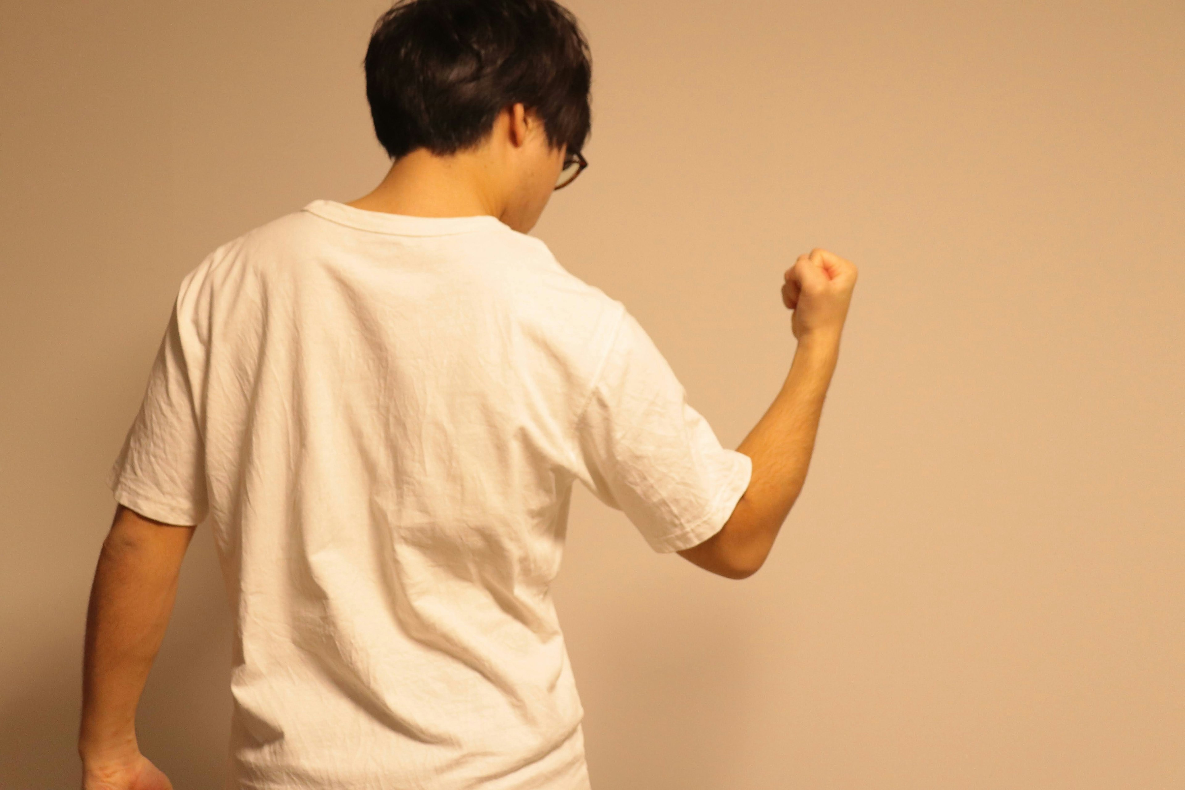 A man in a white t-shirt facing away with a raised fist