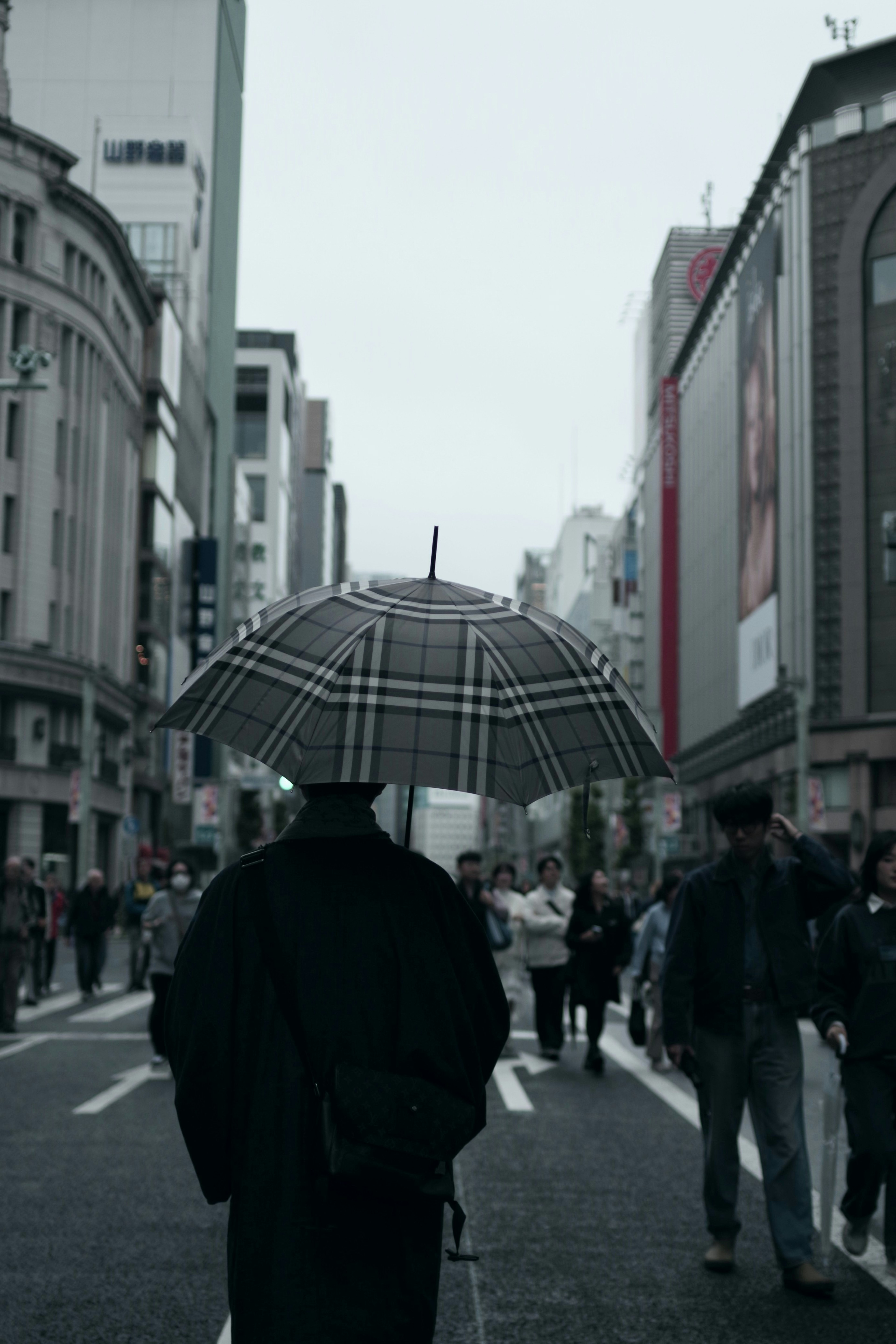 傘を持った人物が街を歩いている風景