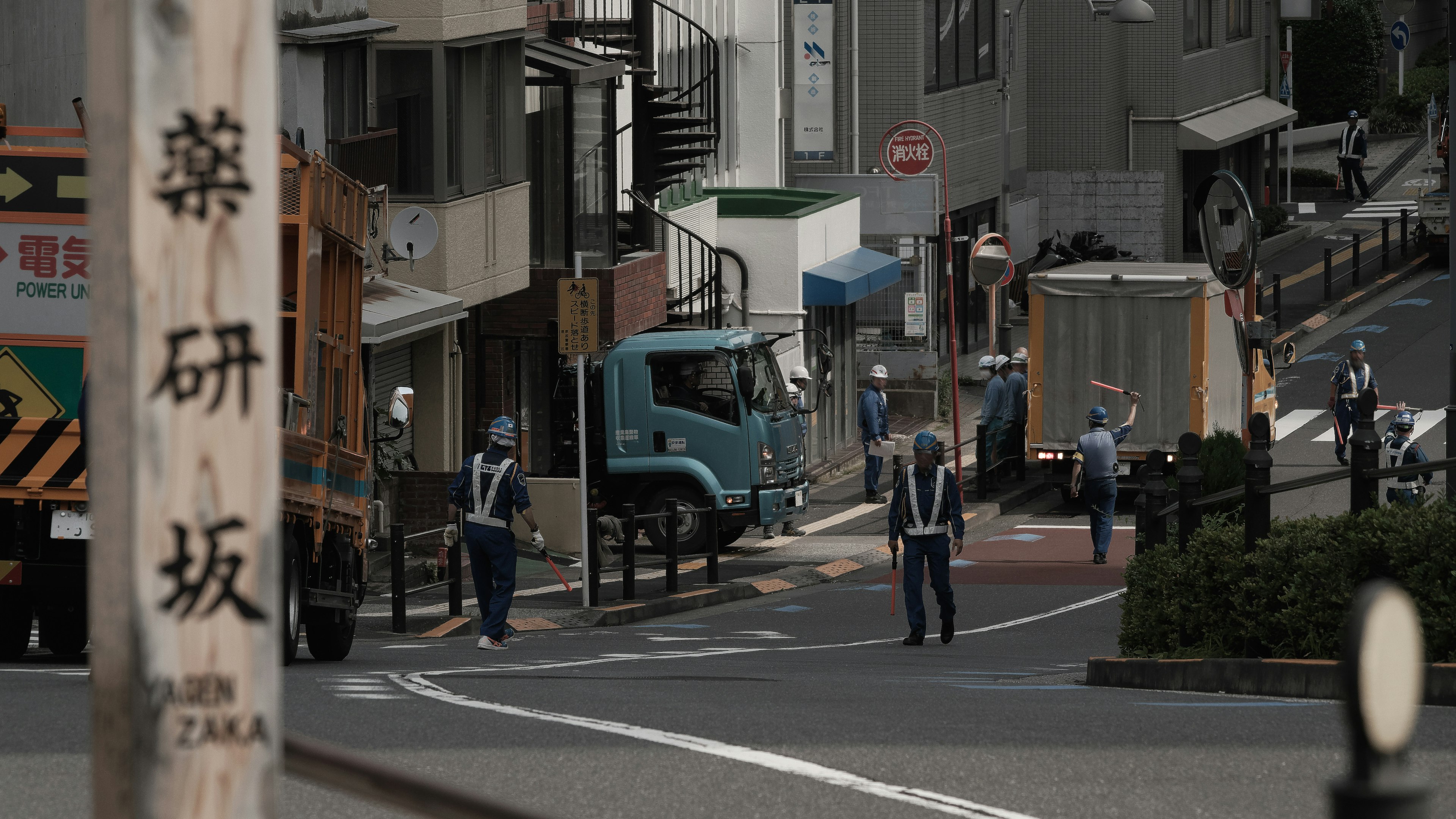 坂道に立つ警察官とトラックが並ぶ都市の風景