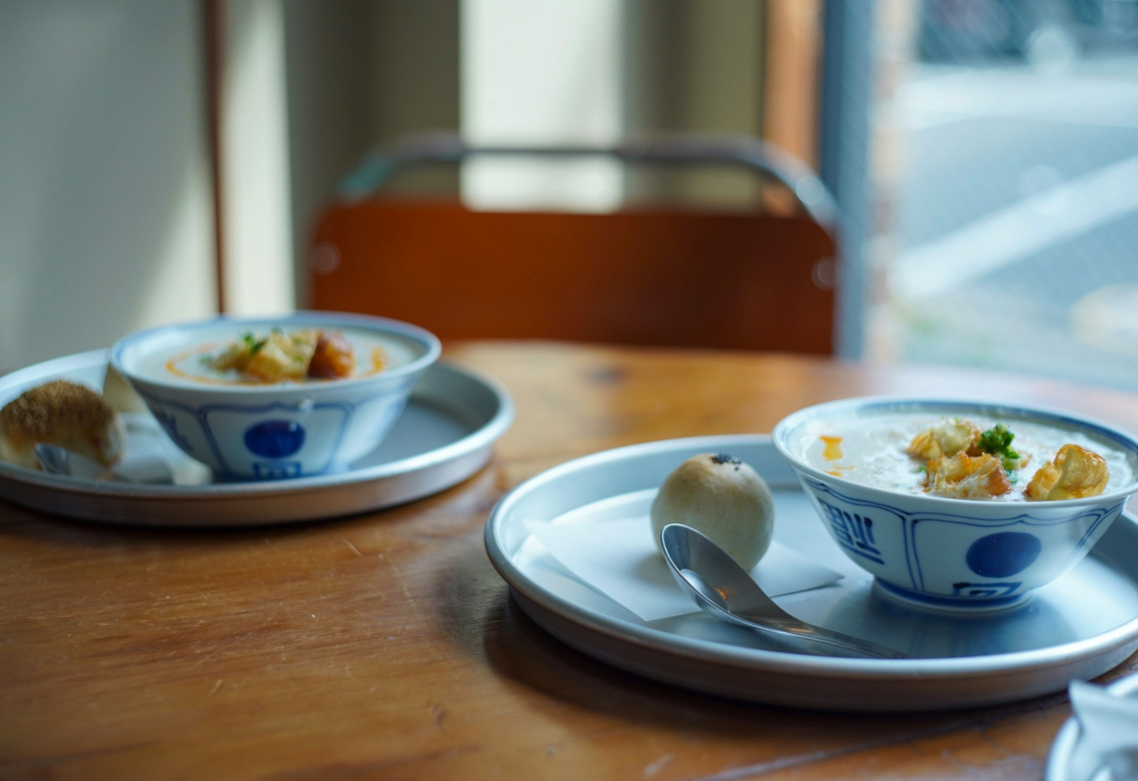 Two bowls of food on plates placed on a wooden table