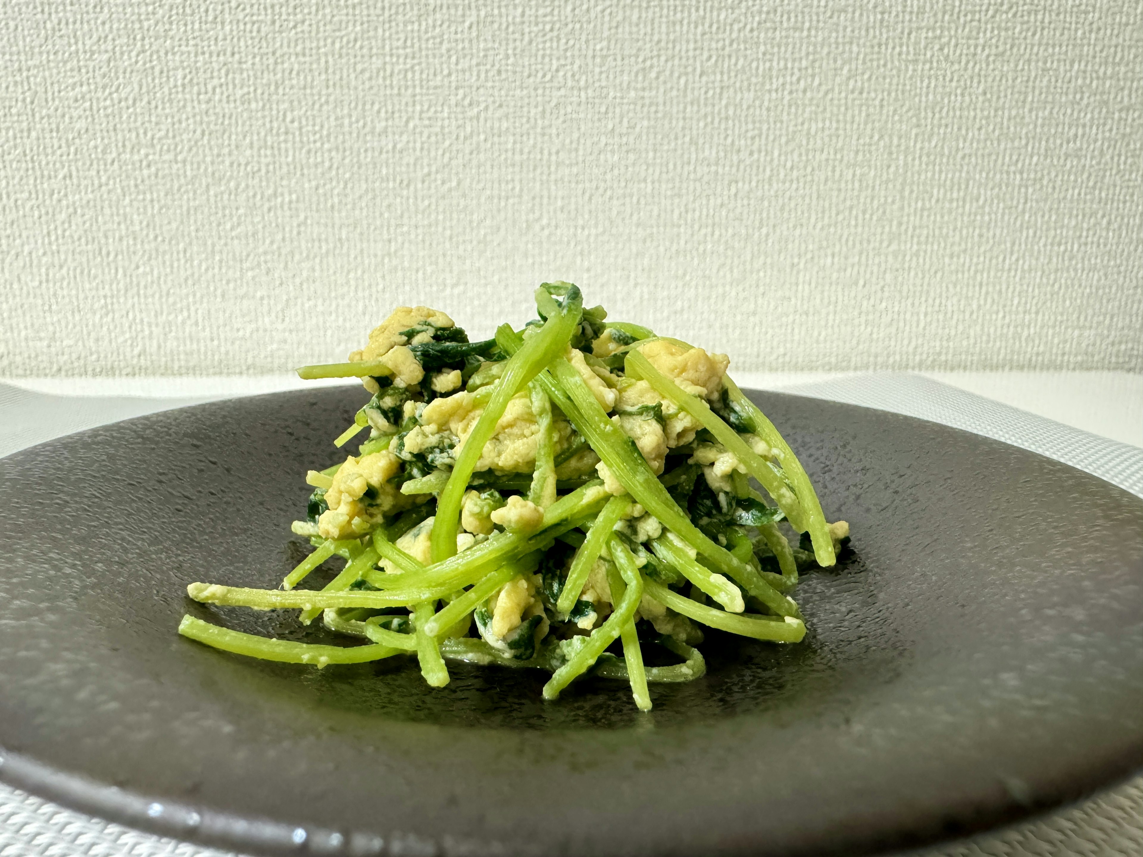 Salad of green vegetables served on a black plate