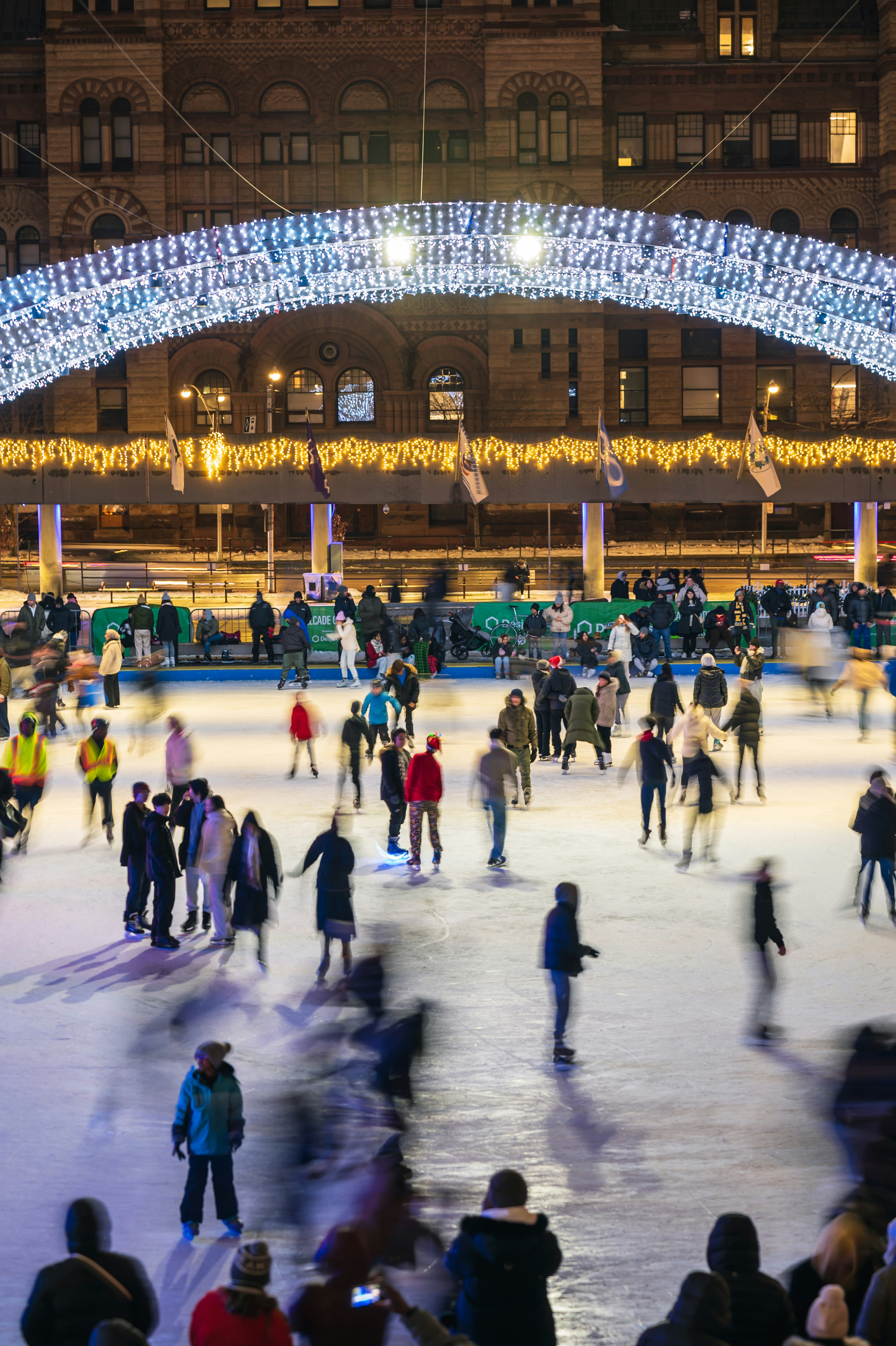 Menschen, die nachts auf einer Eisbahn mit einem Lichtbogen skaten