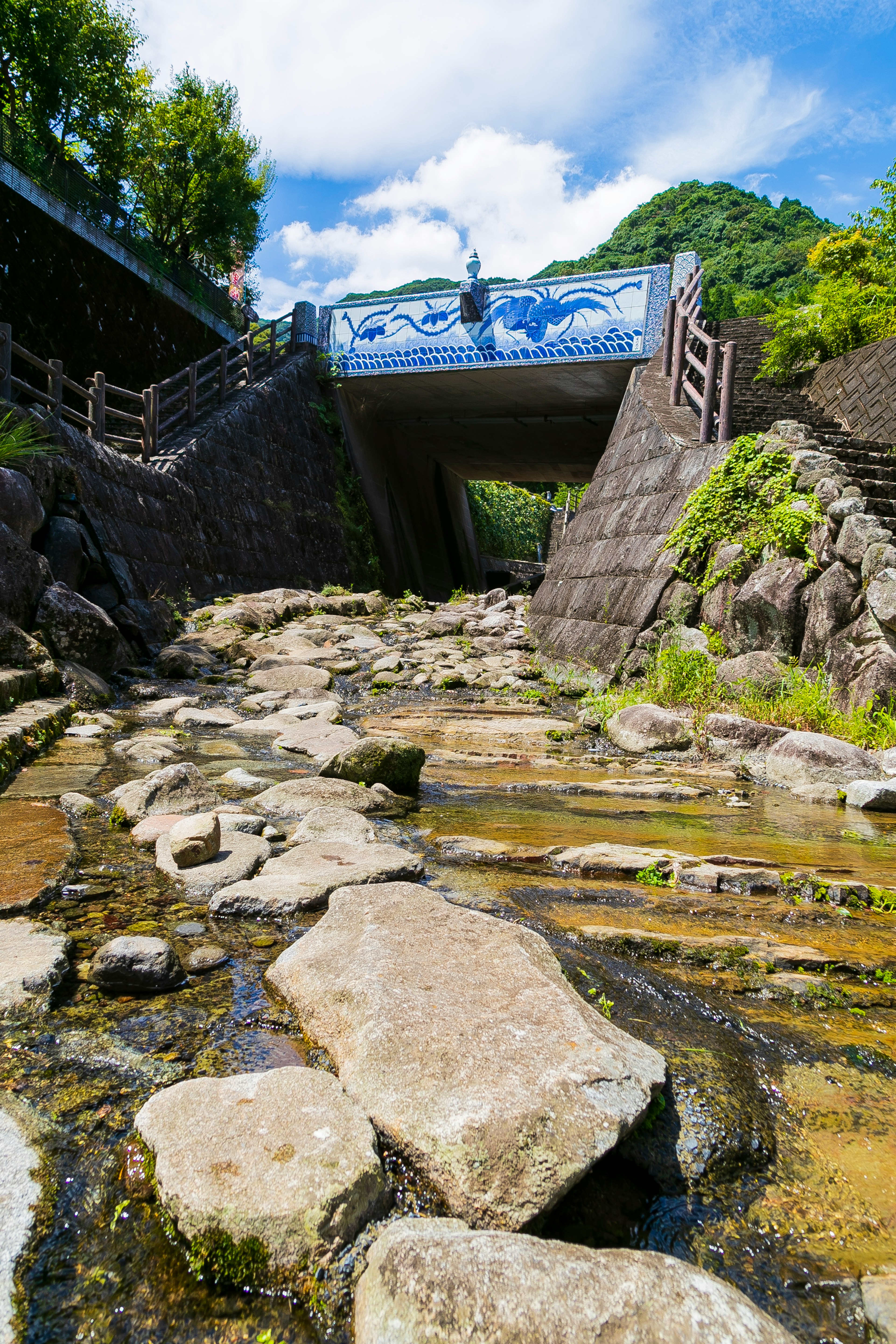 Un torrente con rocce sparse e un ponte sullo sfondo