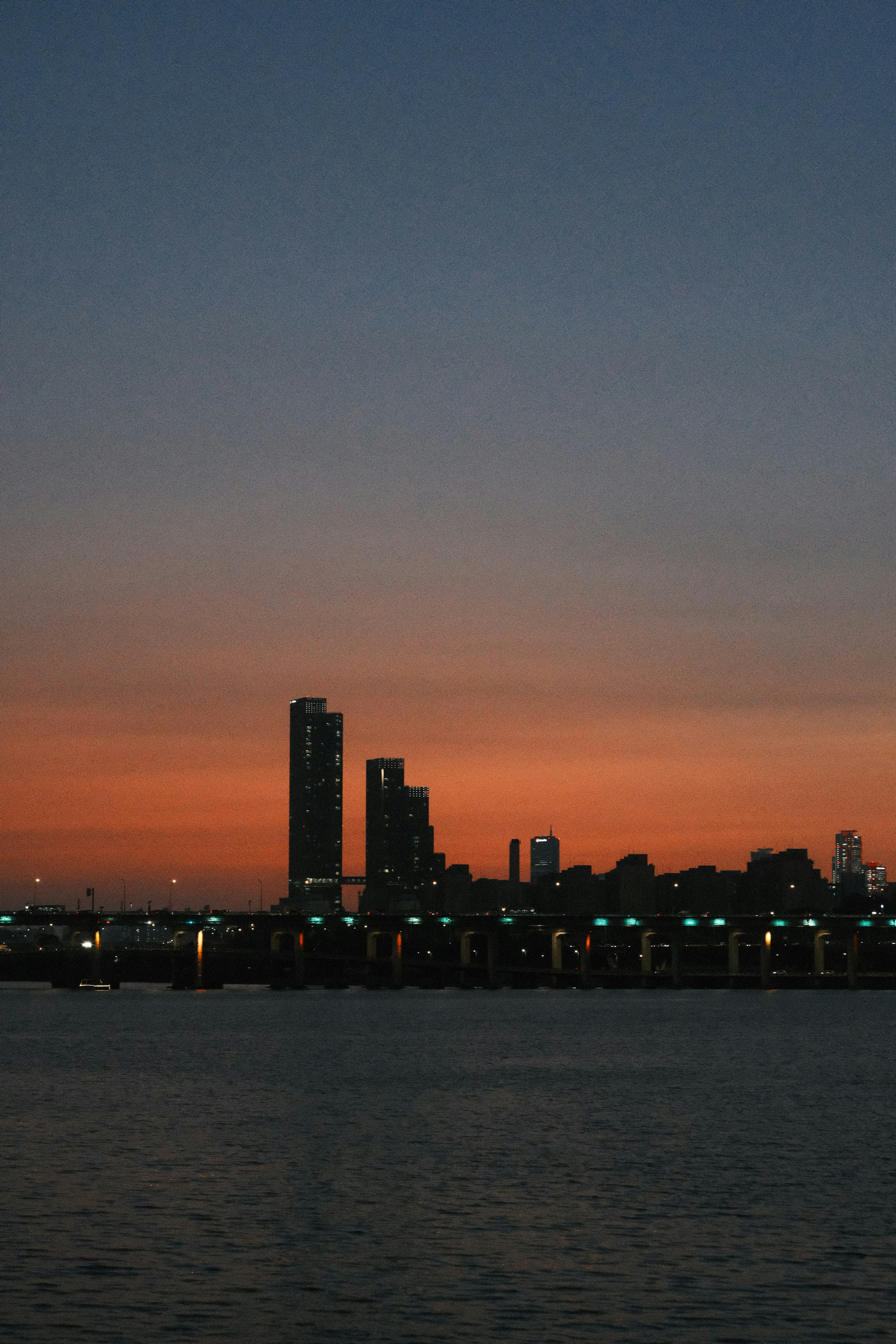 Silhouette d'une ville au coucher du soleil avec des reflets sur l'eau