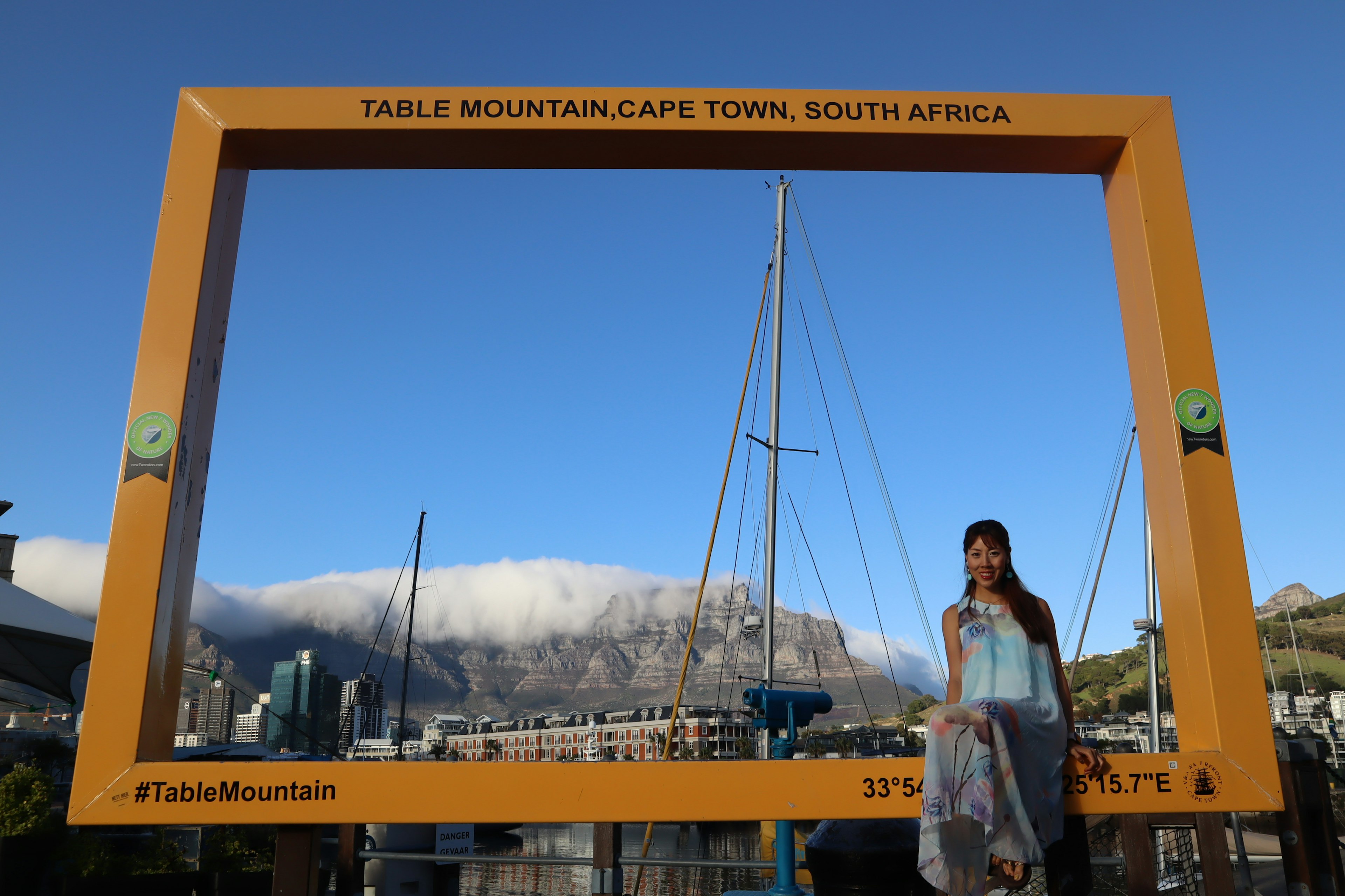 A woman poses in front of a large frame with Table Mountain in the background