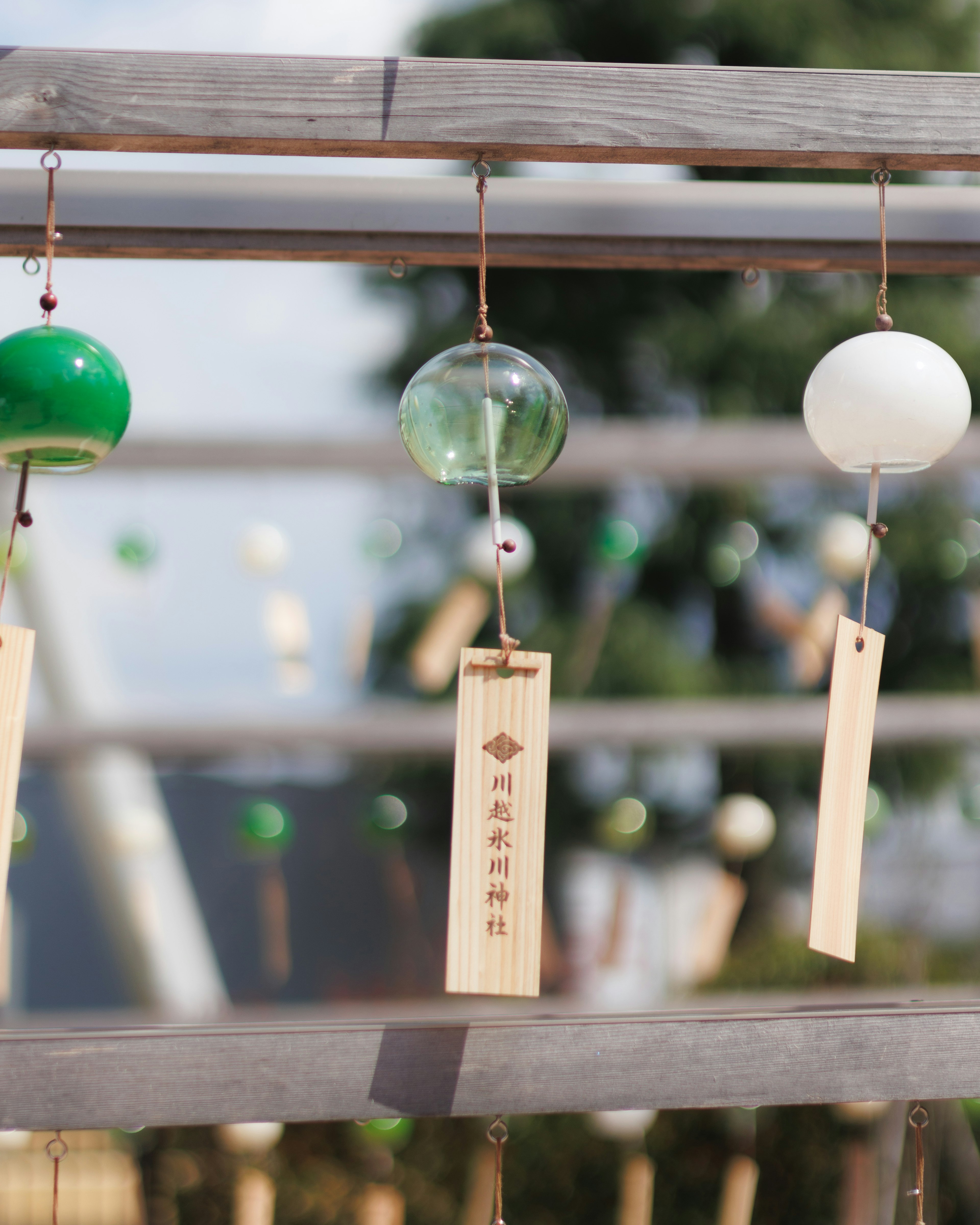 Colorful wind chimes hanging from a wooden frame with a clear sky