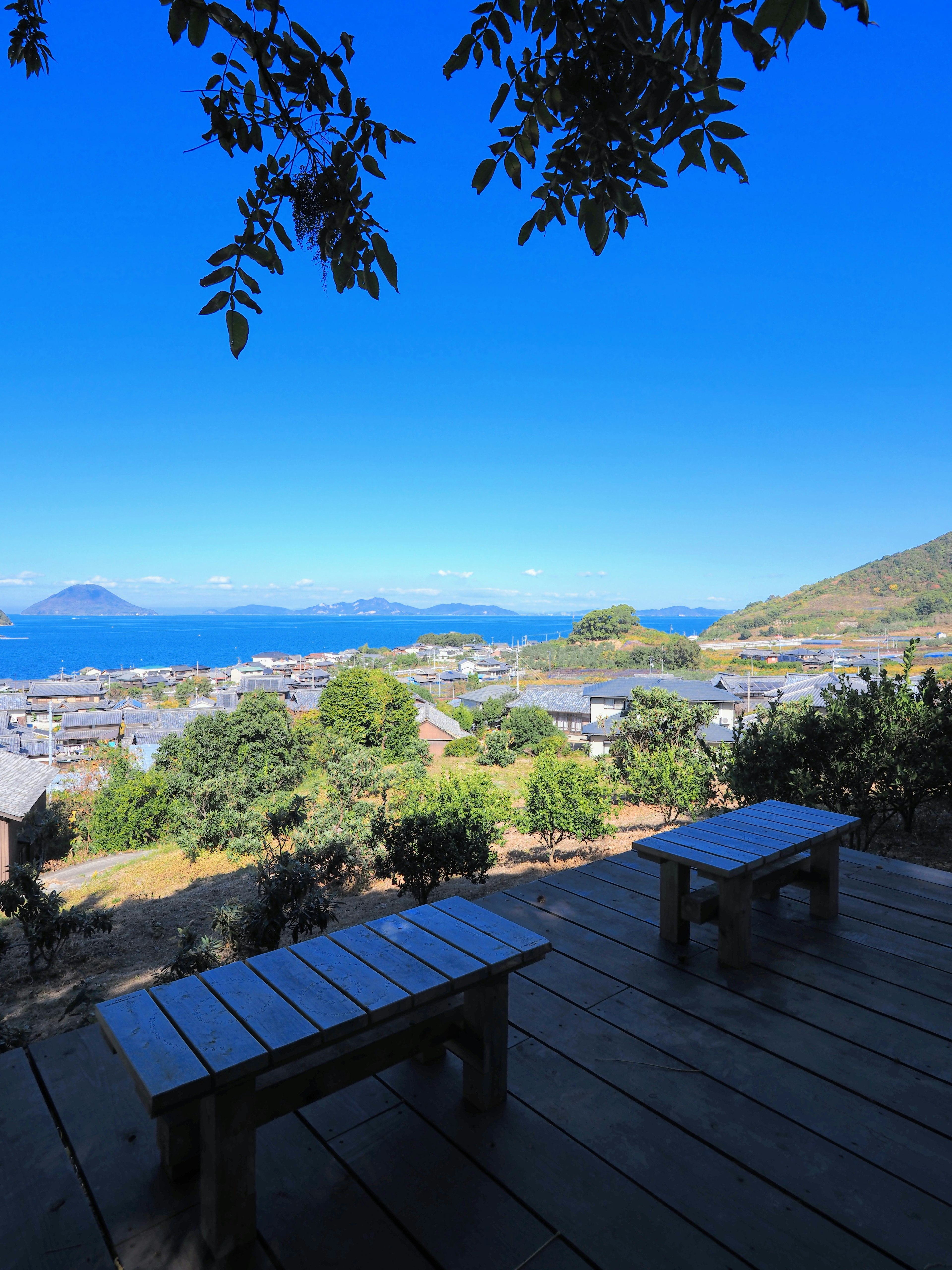 Mesas y sillas de madera con vista a un hermoso paisaje con cielo azul y mar