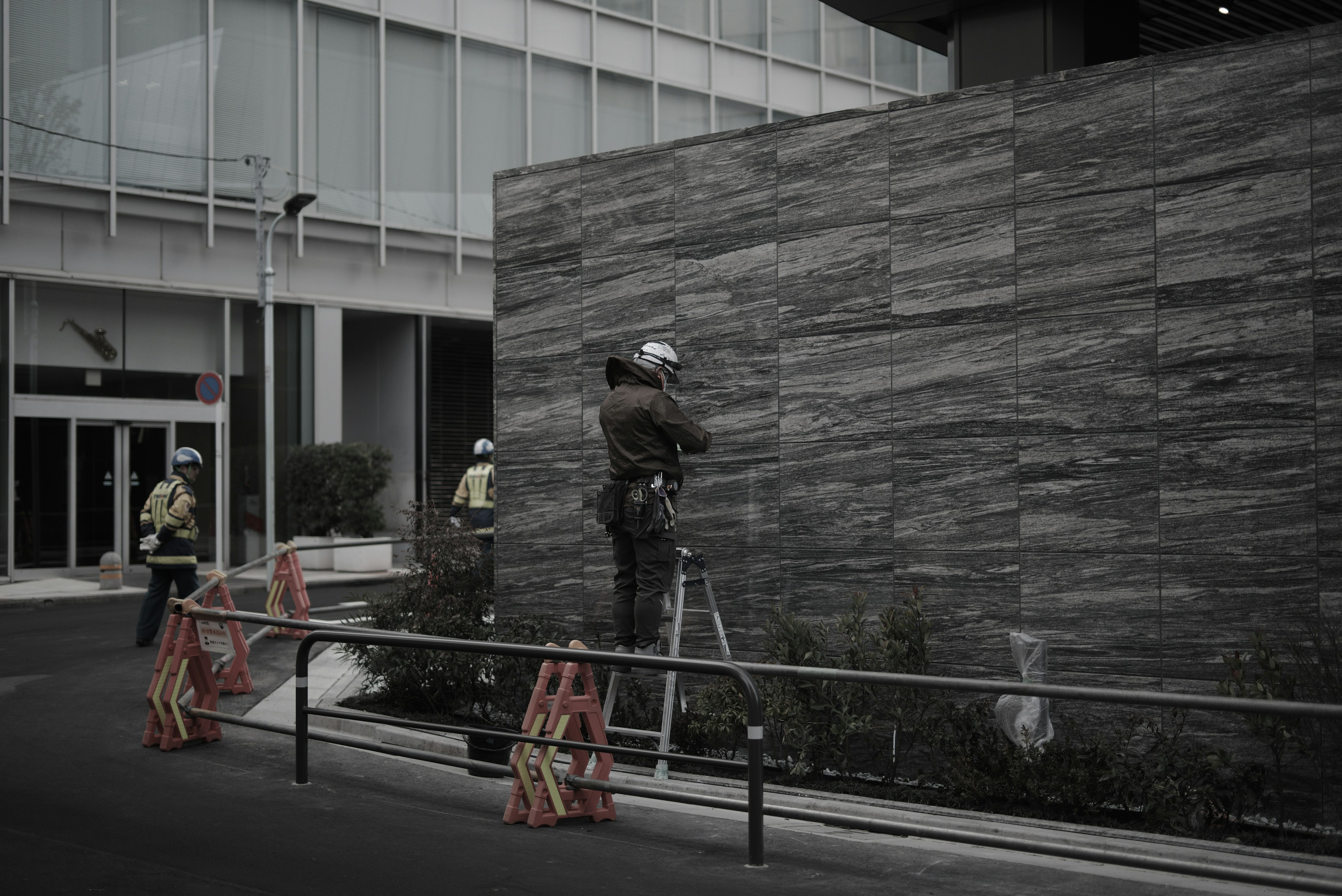 Trabajadores con equipo de seguridad reparando una pared de piedra fuera de un edificio