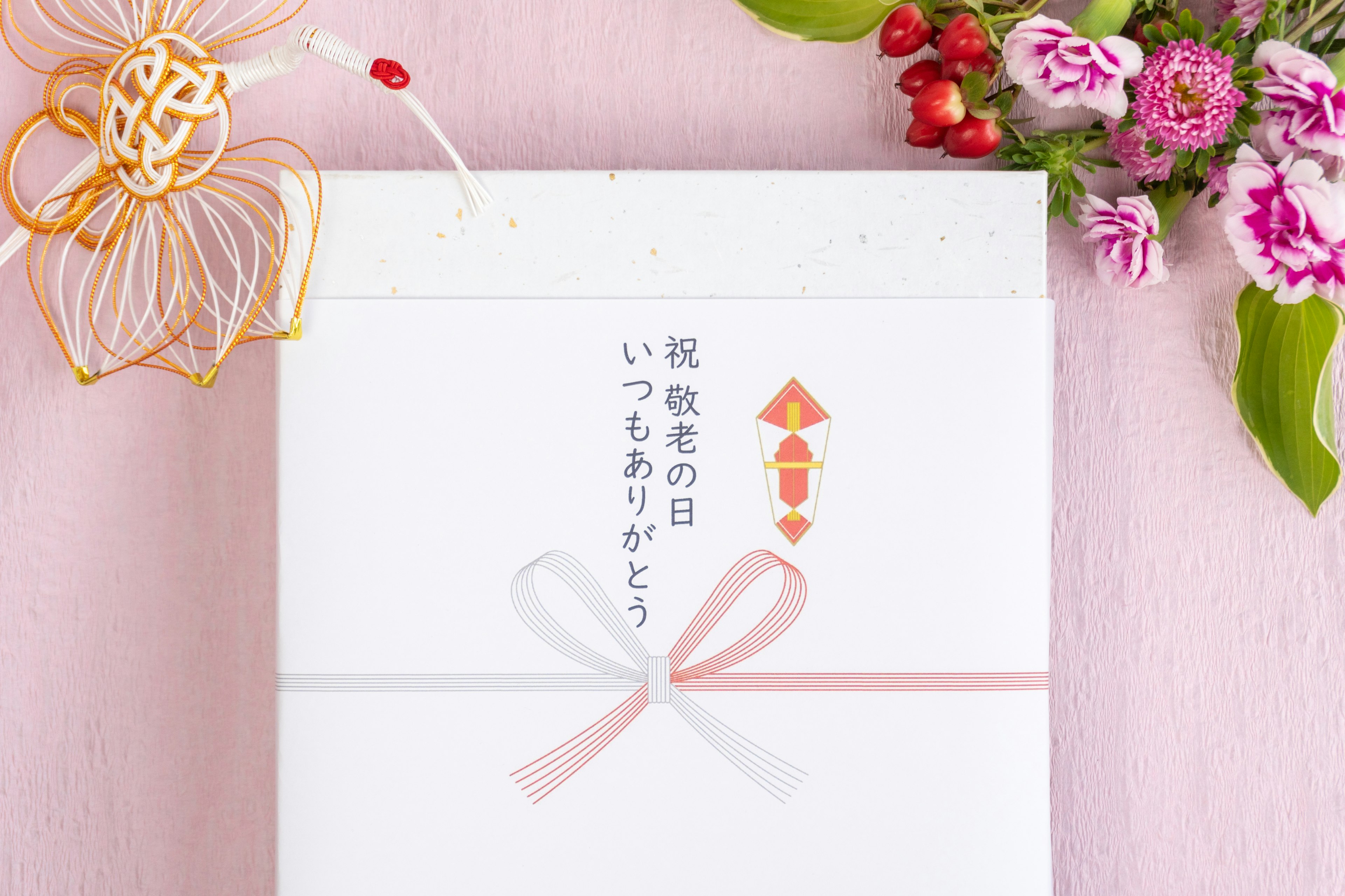 White gift box with a pink ribbon Beautiful floral arrangement with berries