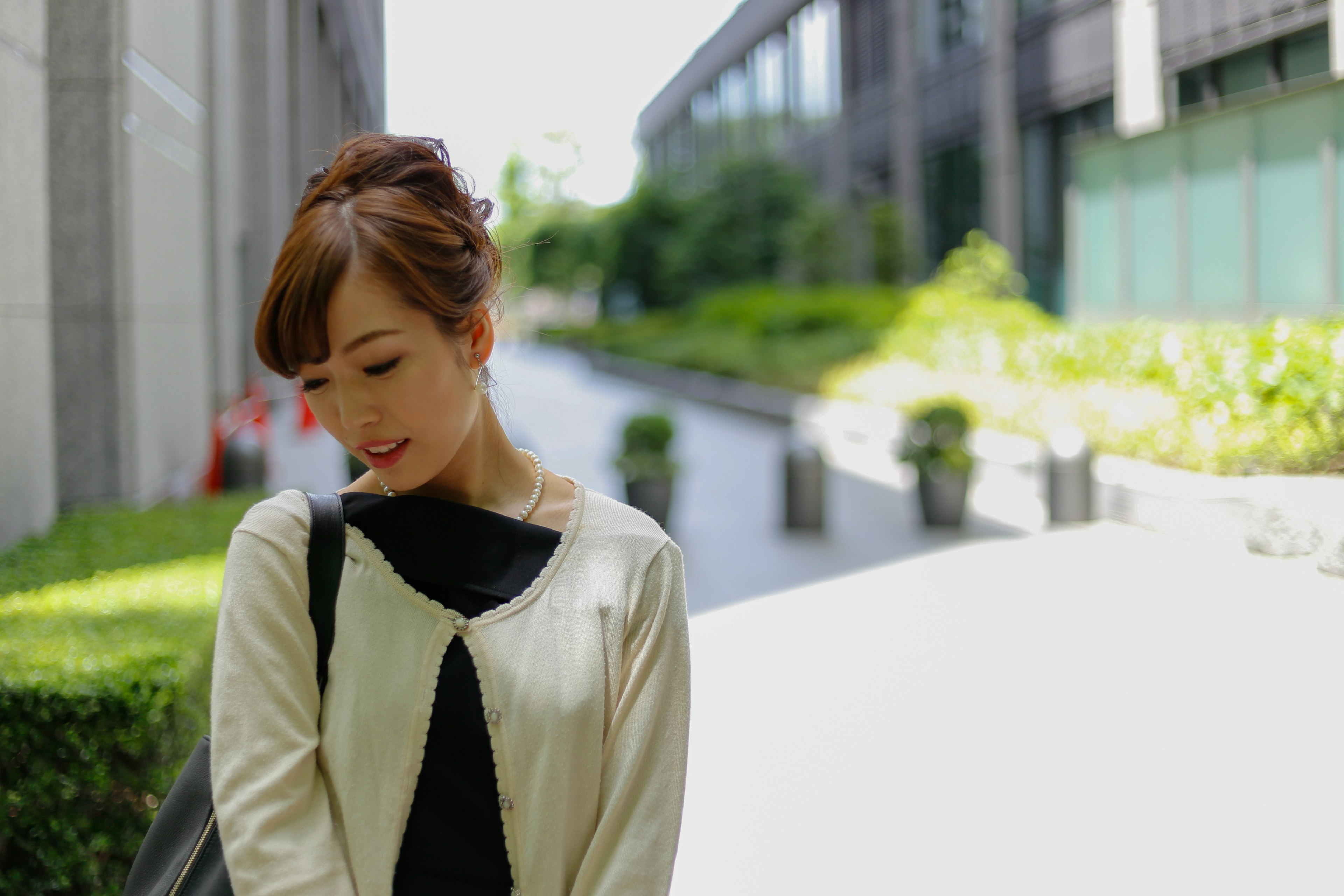 A woman in a white jacket stands in an urban landscape