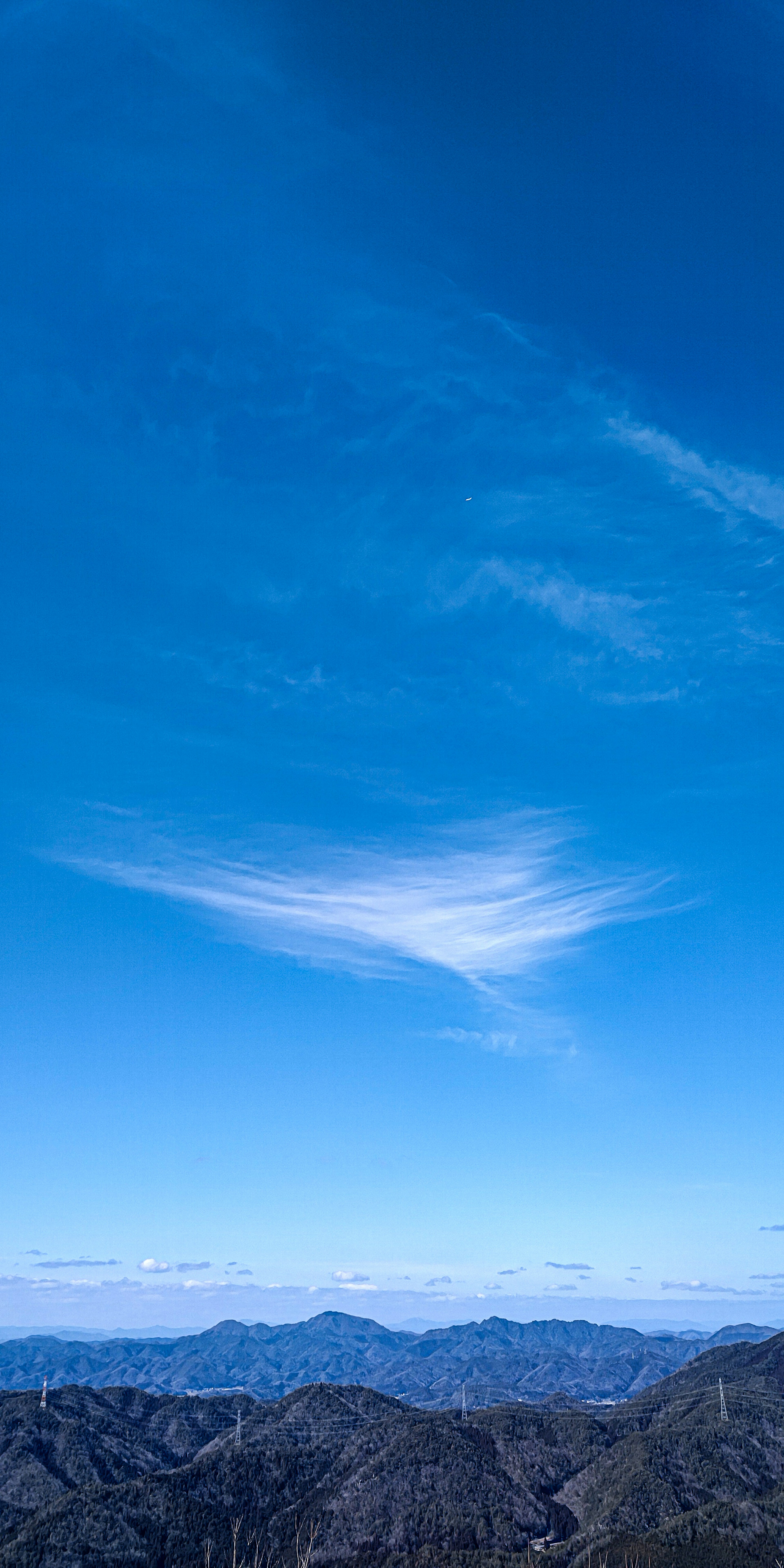 青空と山々が広がる風景に、雲の流れが浮かぶ