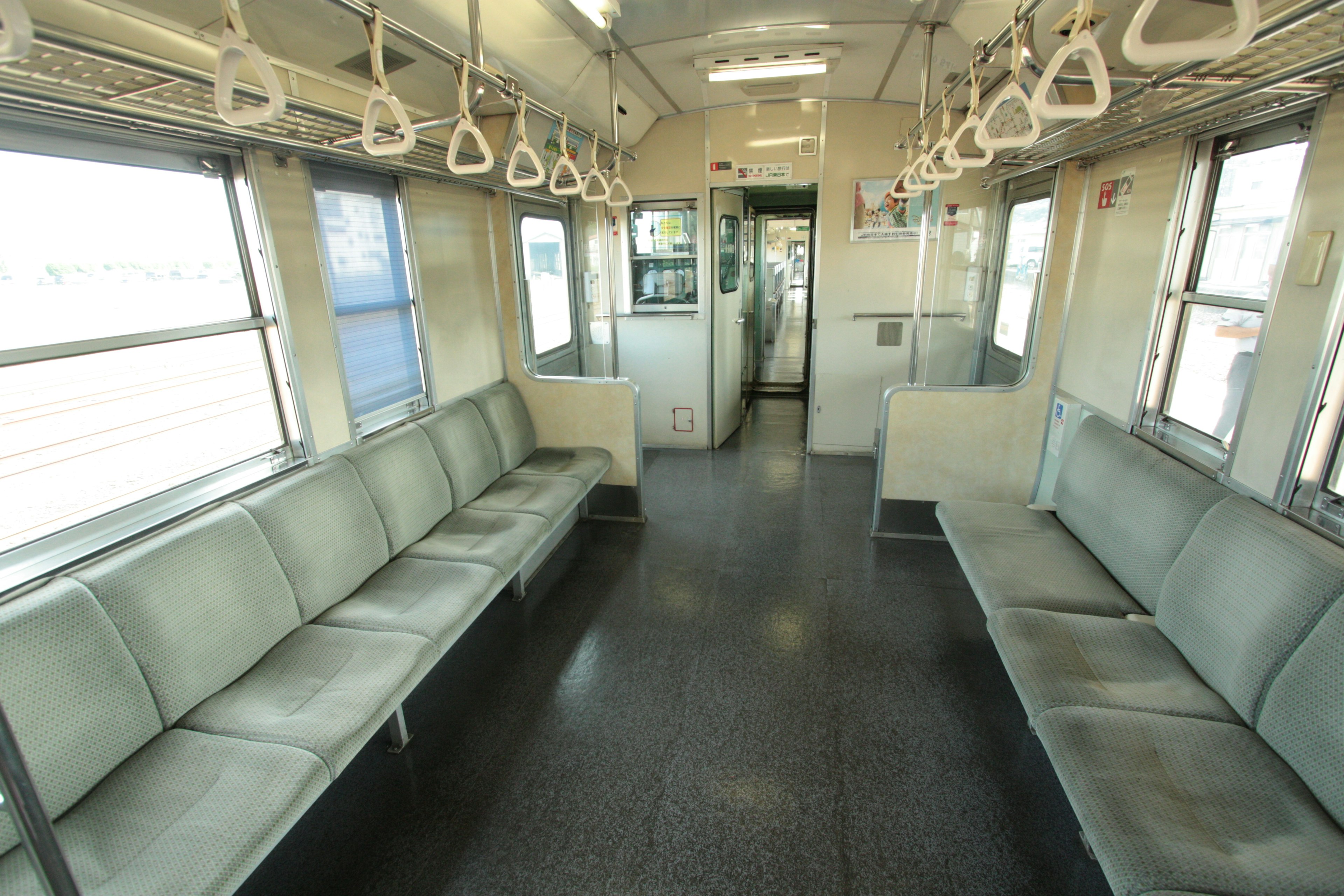 Interior of a train with empty seats and hanging handles