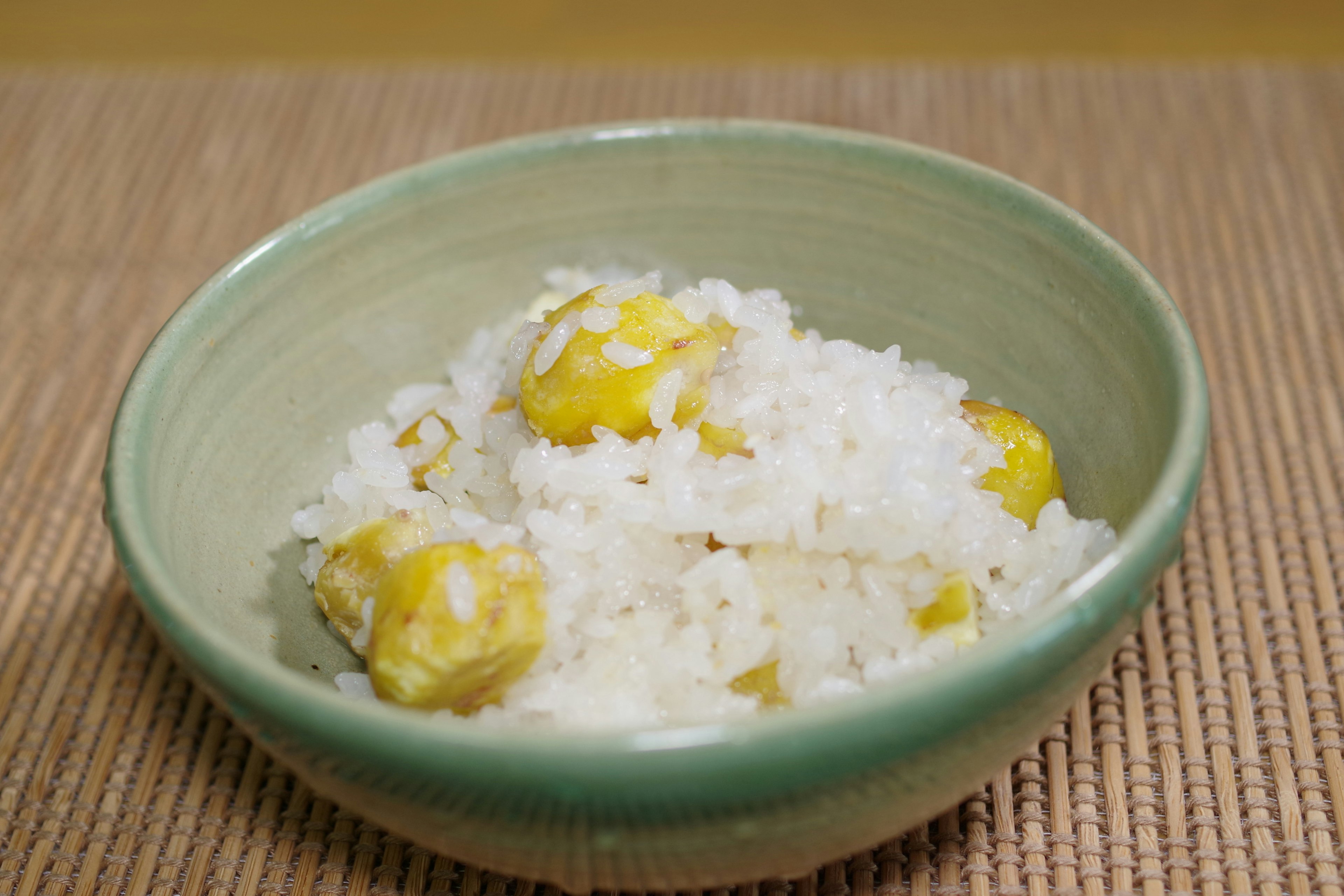 A green bowl filled with rice and chestnuts