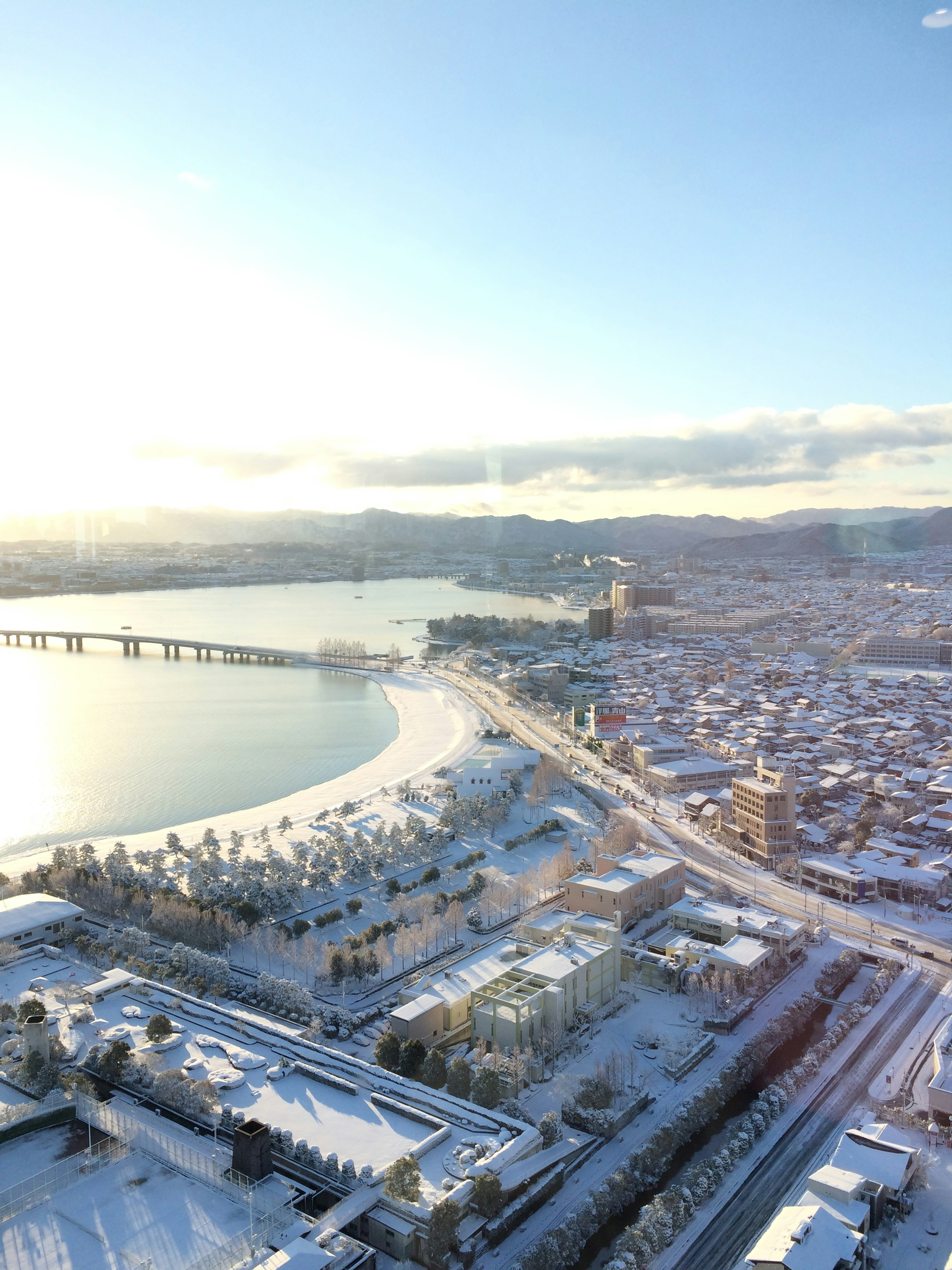 Aerial view of a snow-covered city with a river and bridge