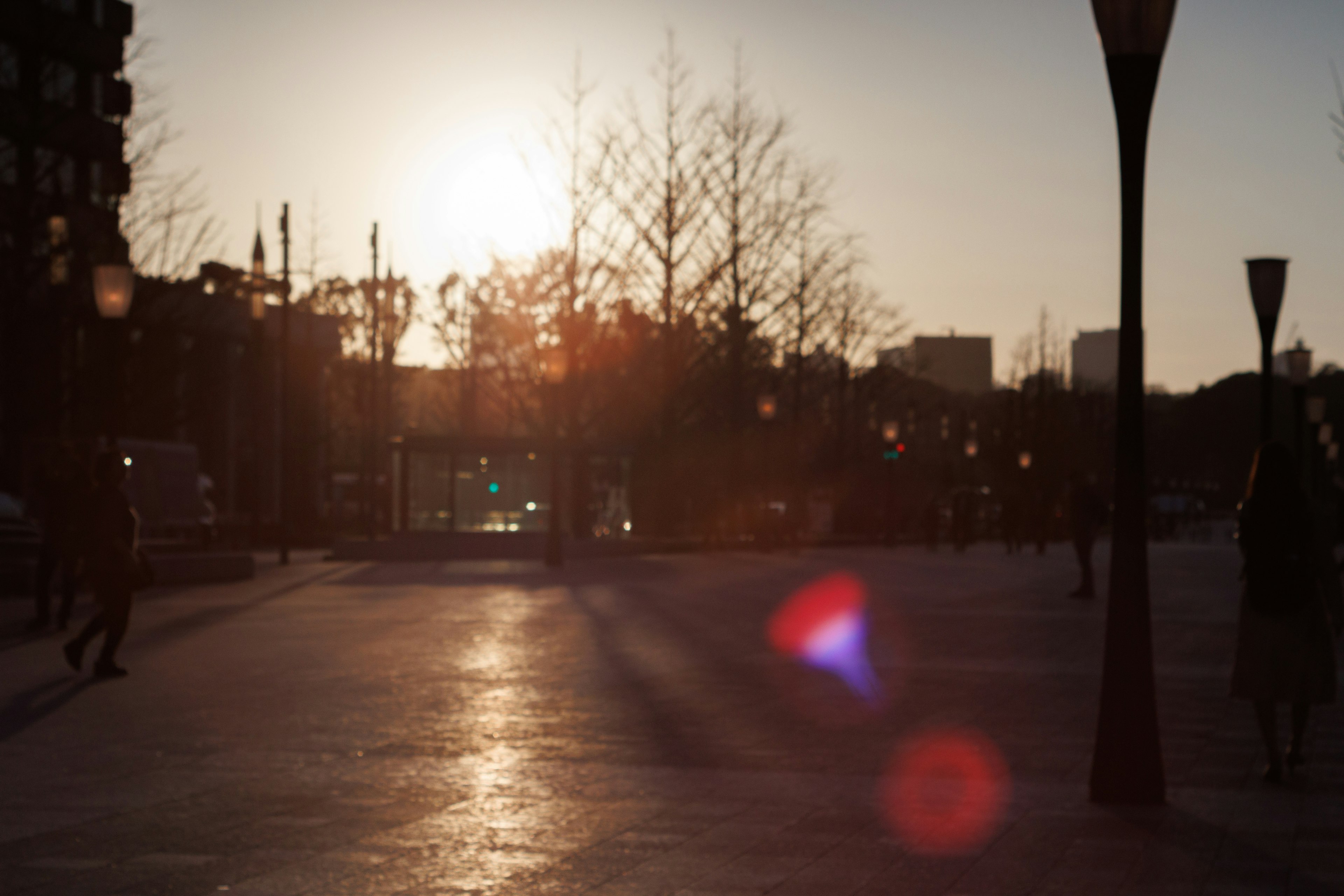 Cityscape at sunset with people walking in the square