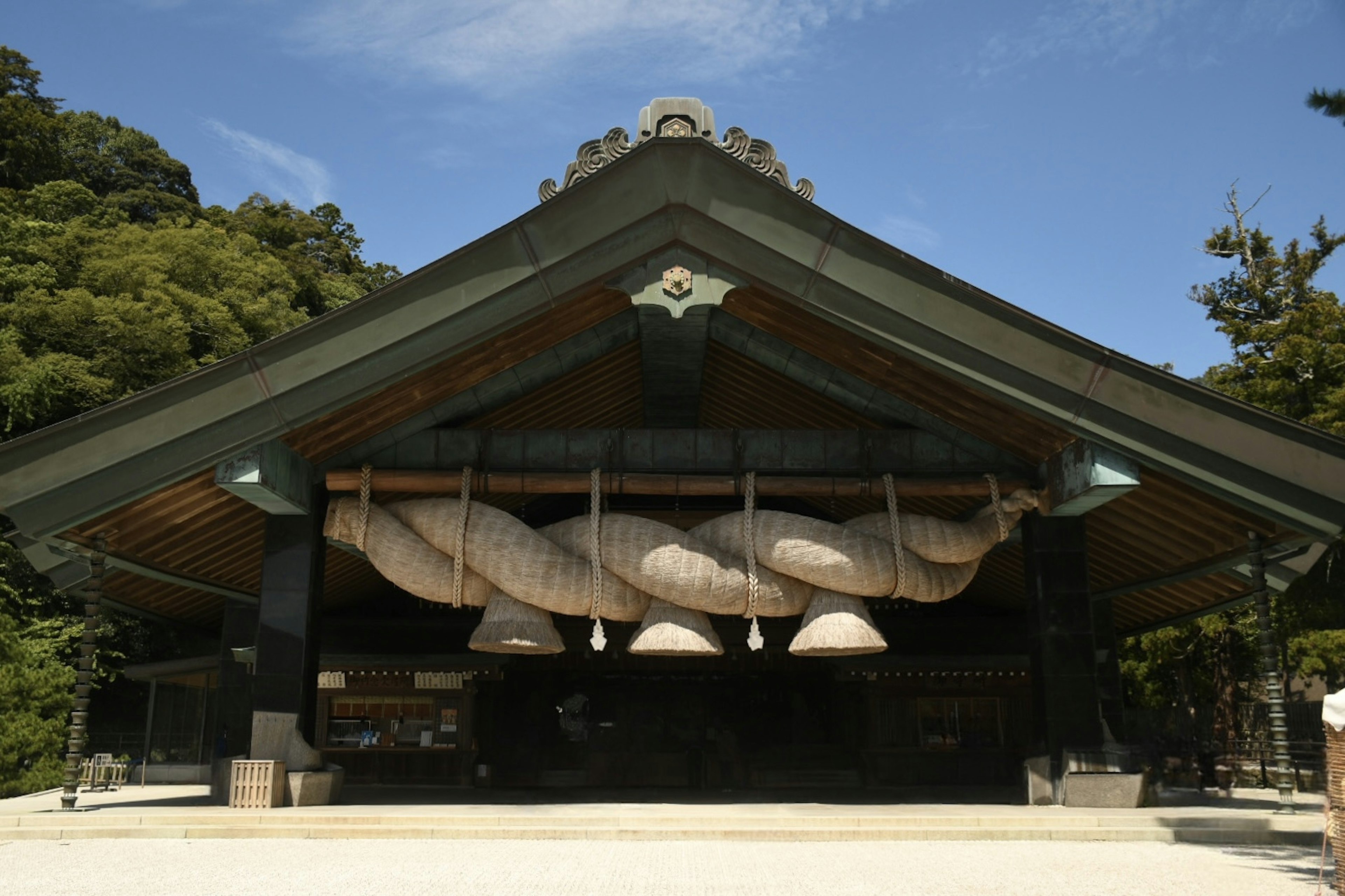 大きな屋根の下に吊るされた巨大な鐘が特徴の神社の外観