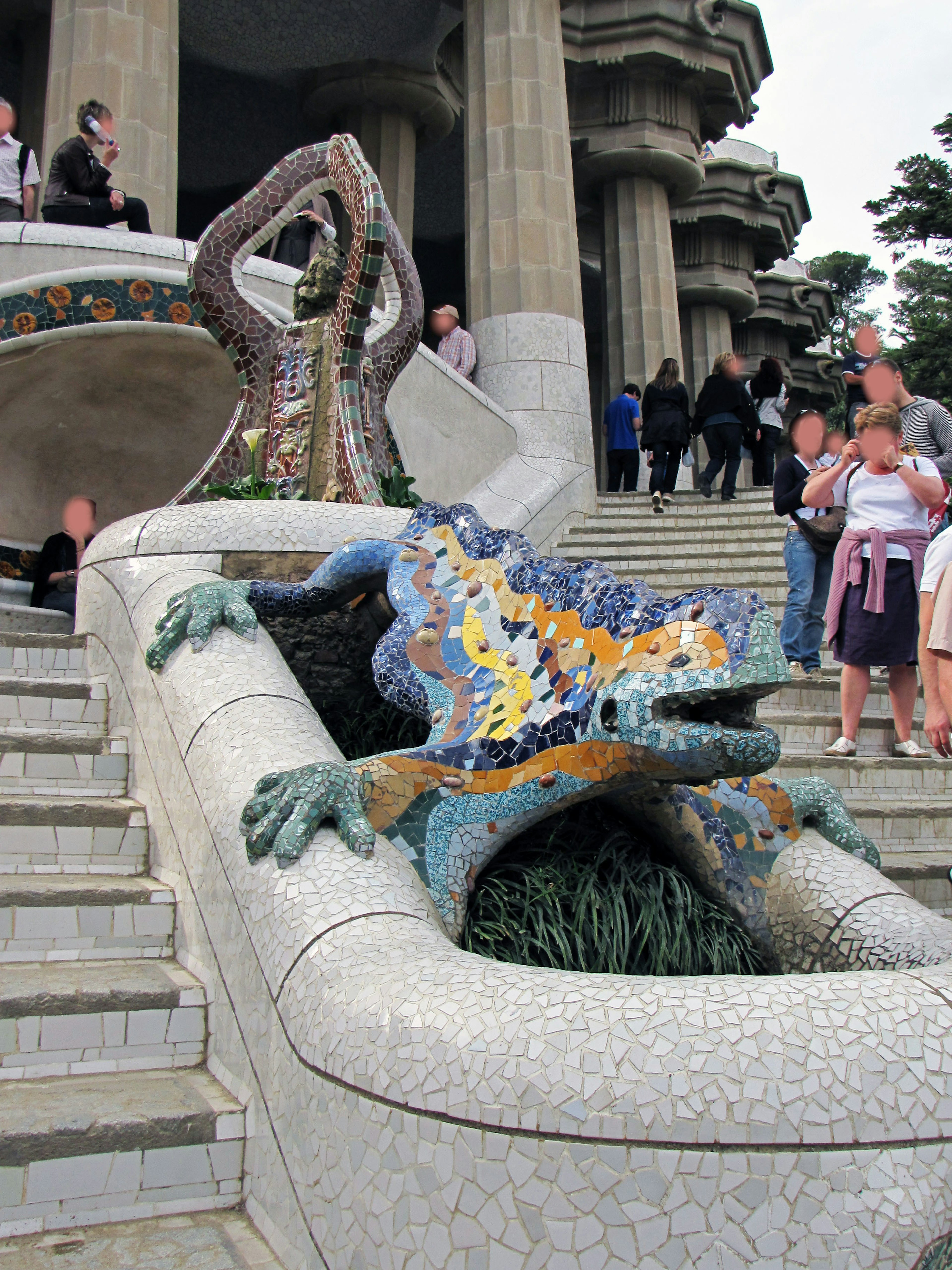 Escultura de lagarto colorido en mosaico en el Parque Güell con visitantes