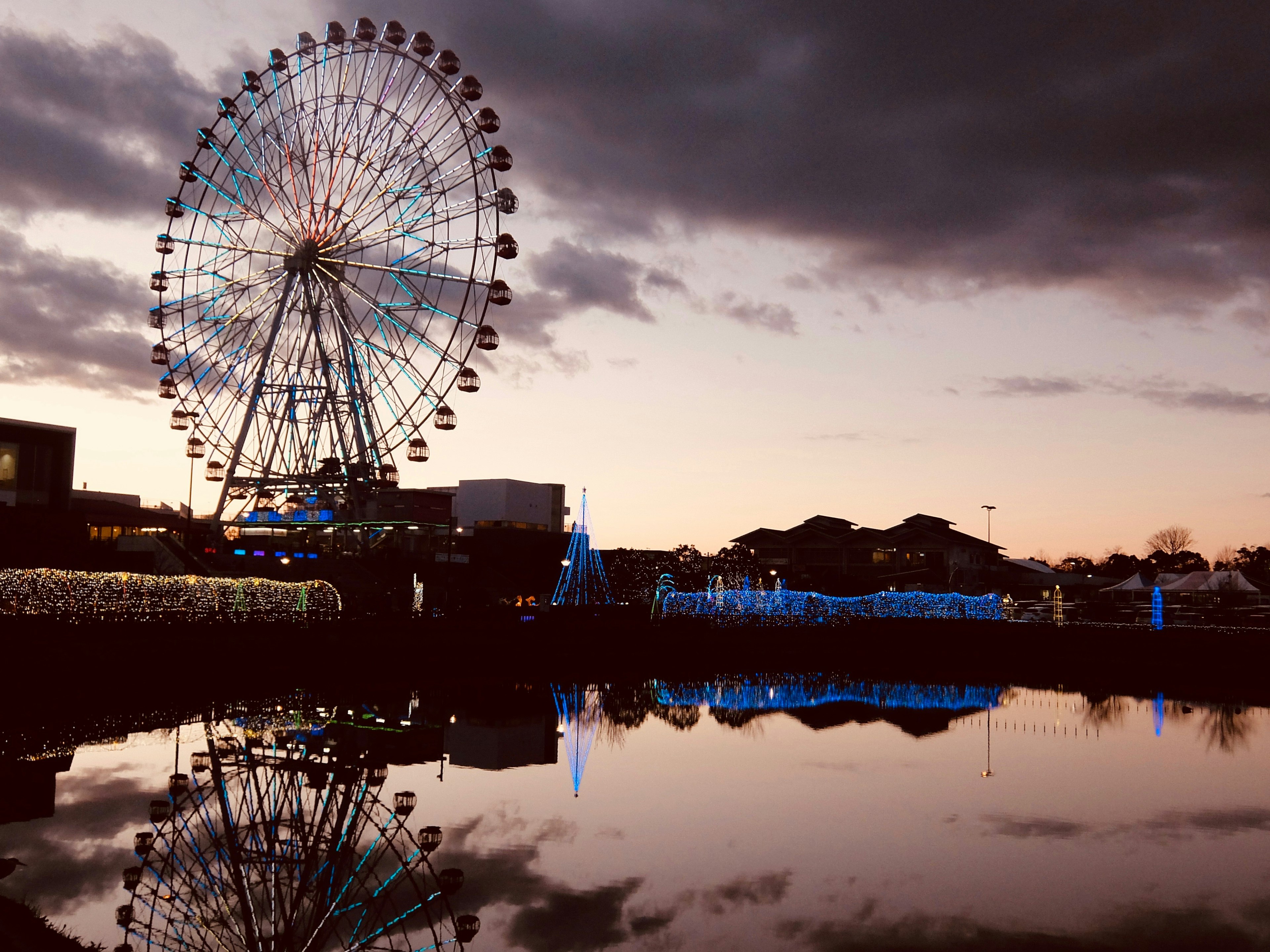 Ferris wheel reflecting on a lake during sunset