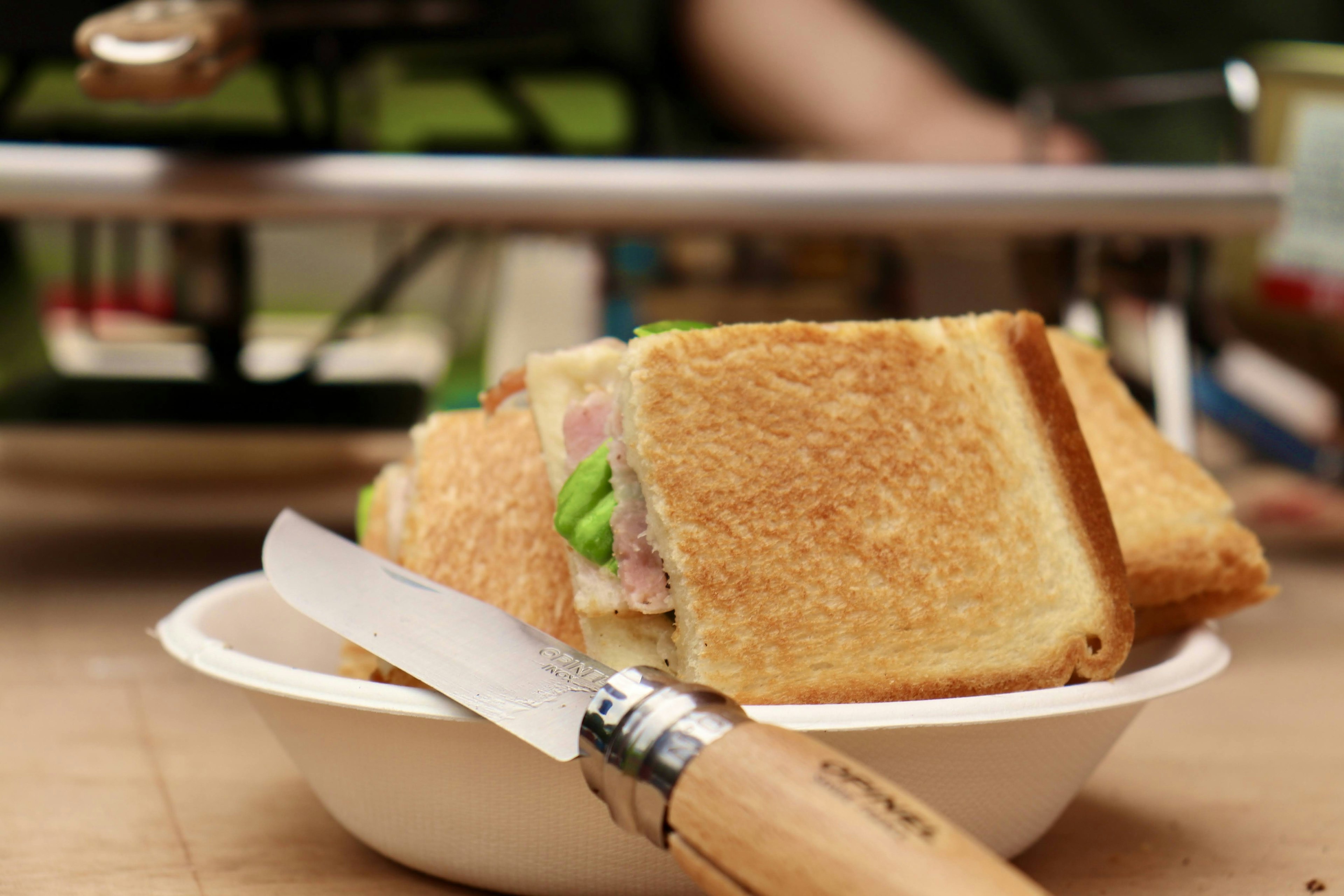 A toasted sandwich placed on a dish with a knife beside it