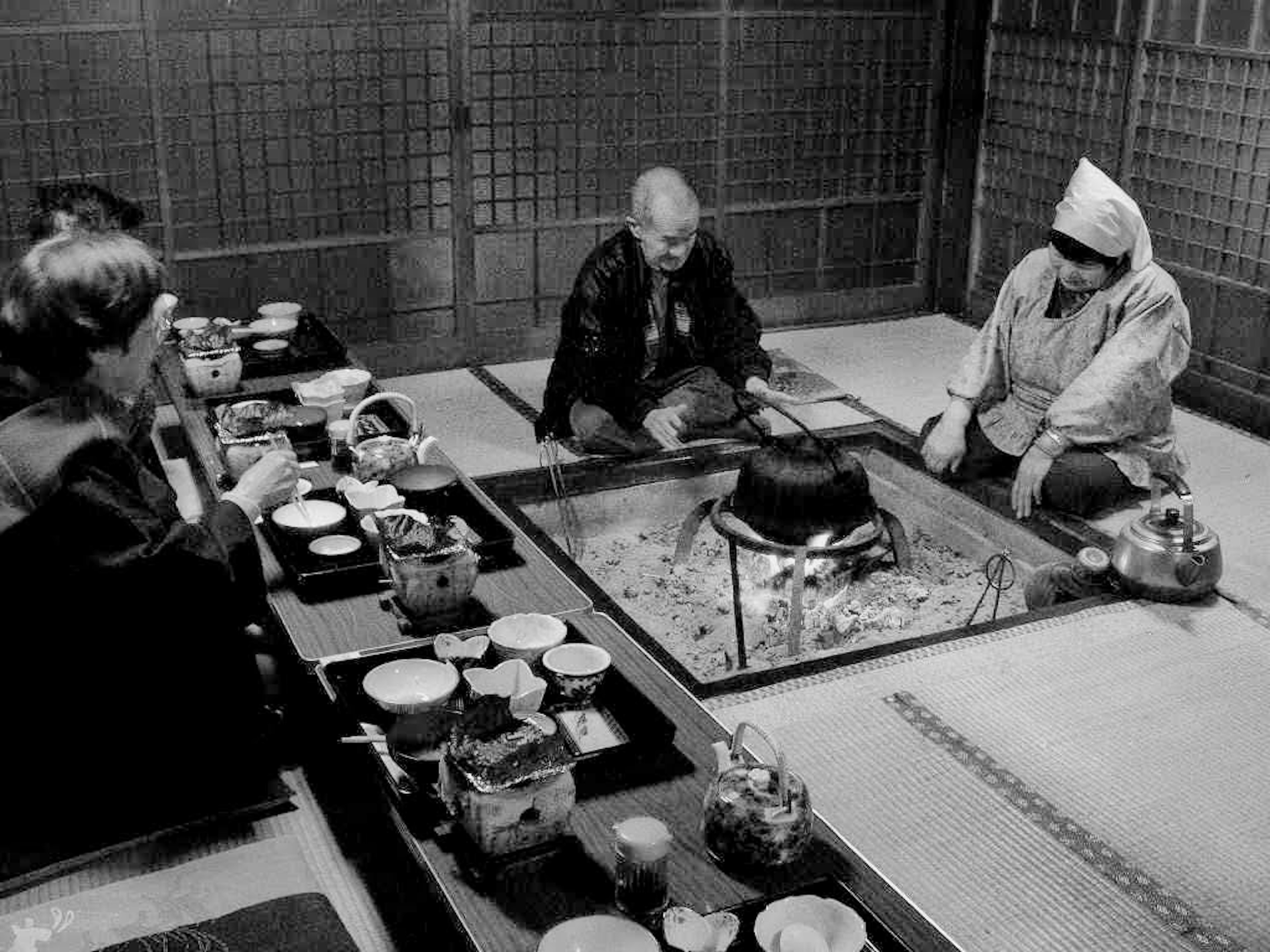 和室で食事をする人々と囲炉裏の風景