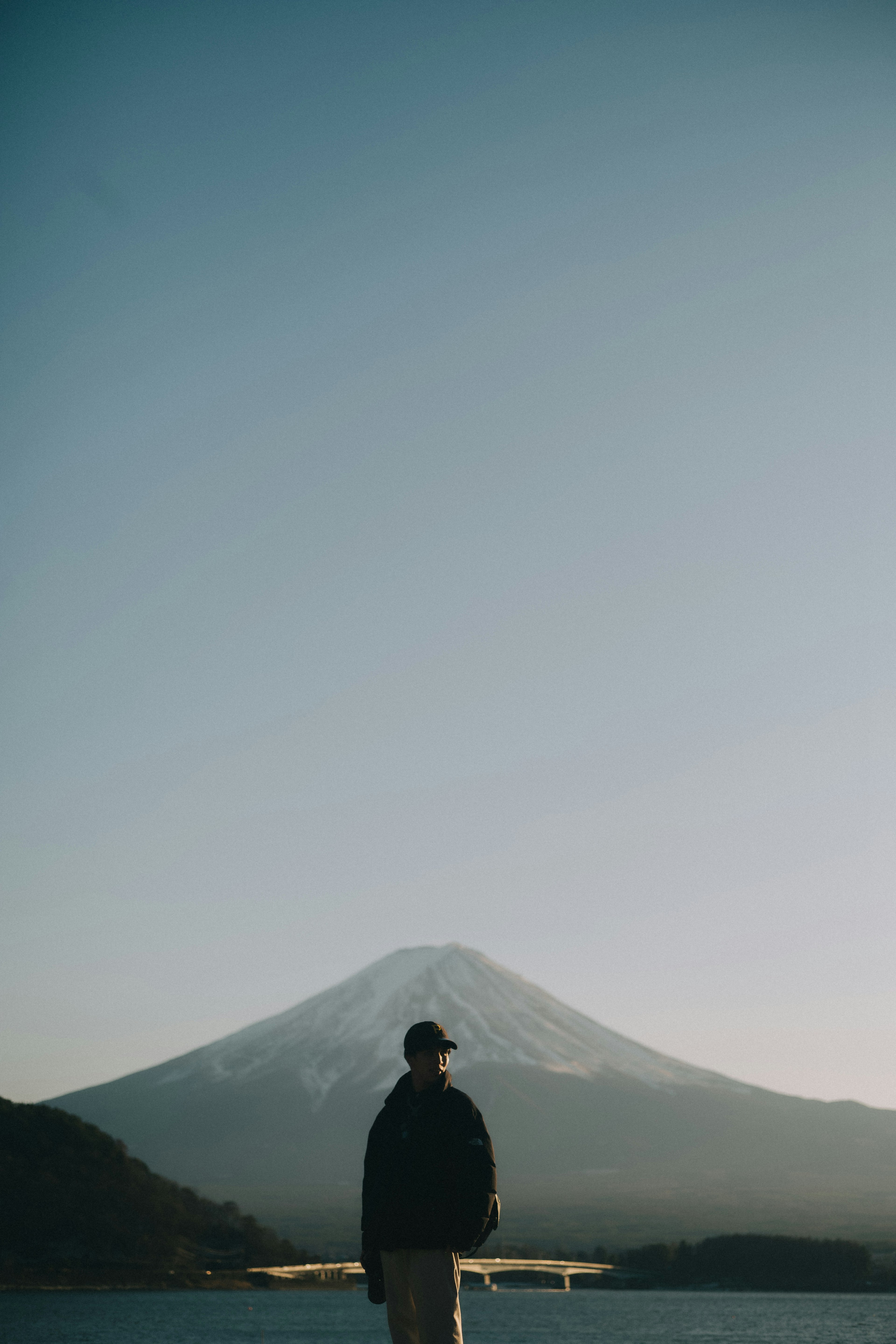 富士山を背景に立つ人物のシルエットと青い空