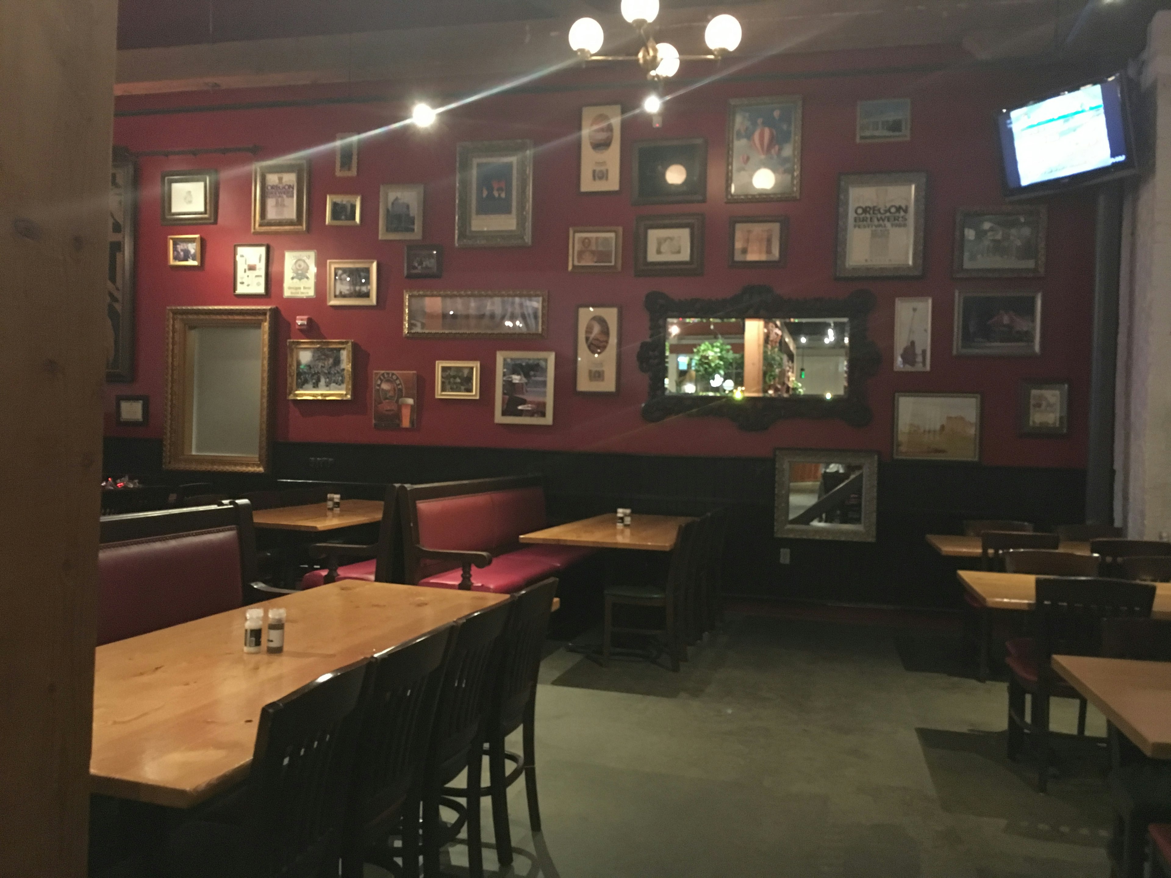 Interior of a restaurant with red walls adorned with framed pictures and wooden tables