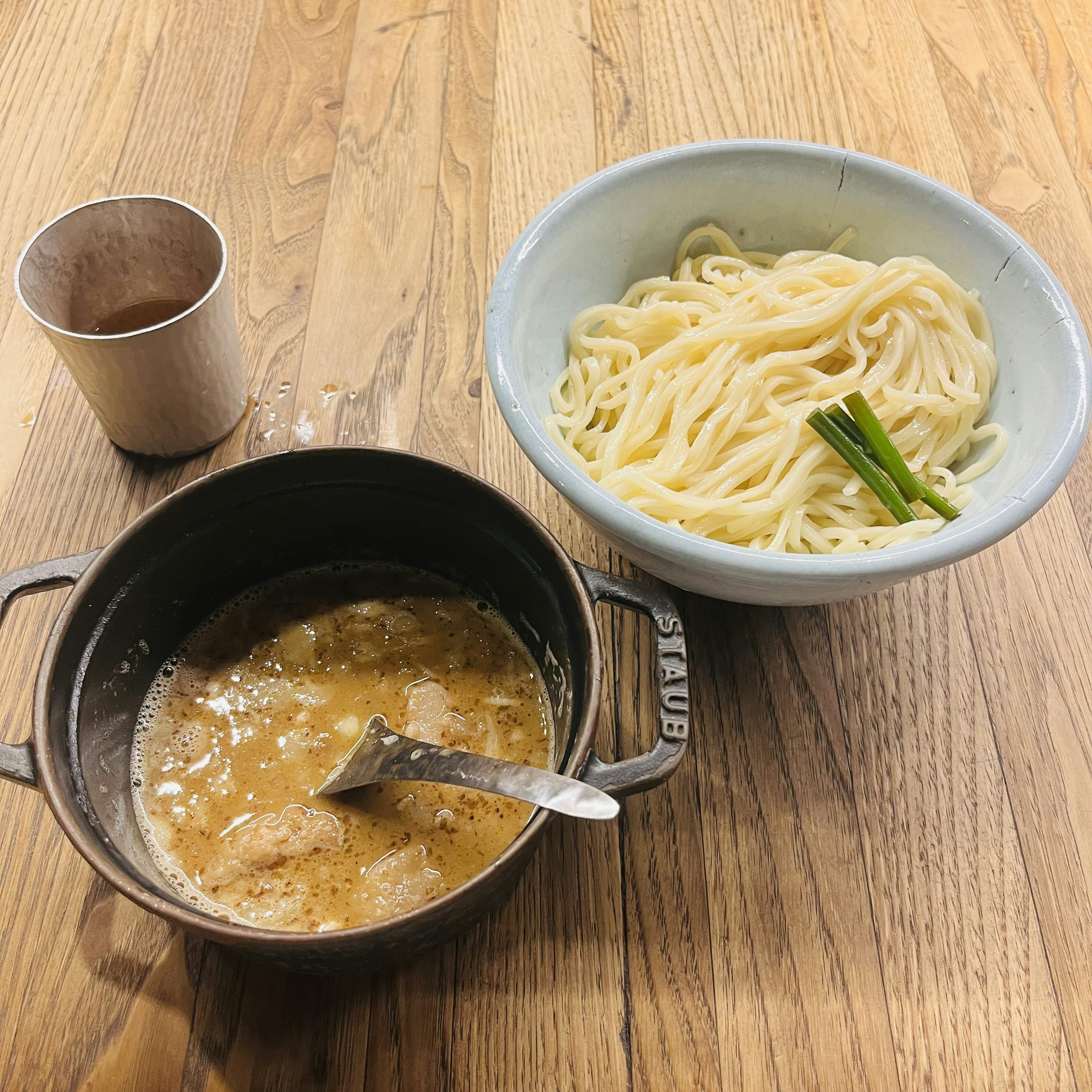 Un piatto di noodles udon con salsa da intingere servito su un tavolo di legno