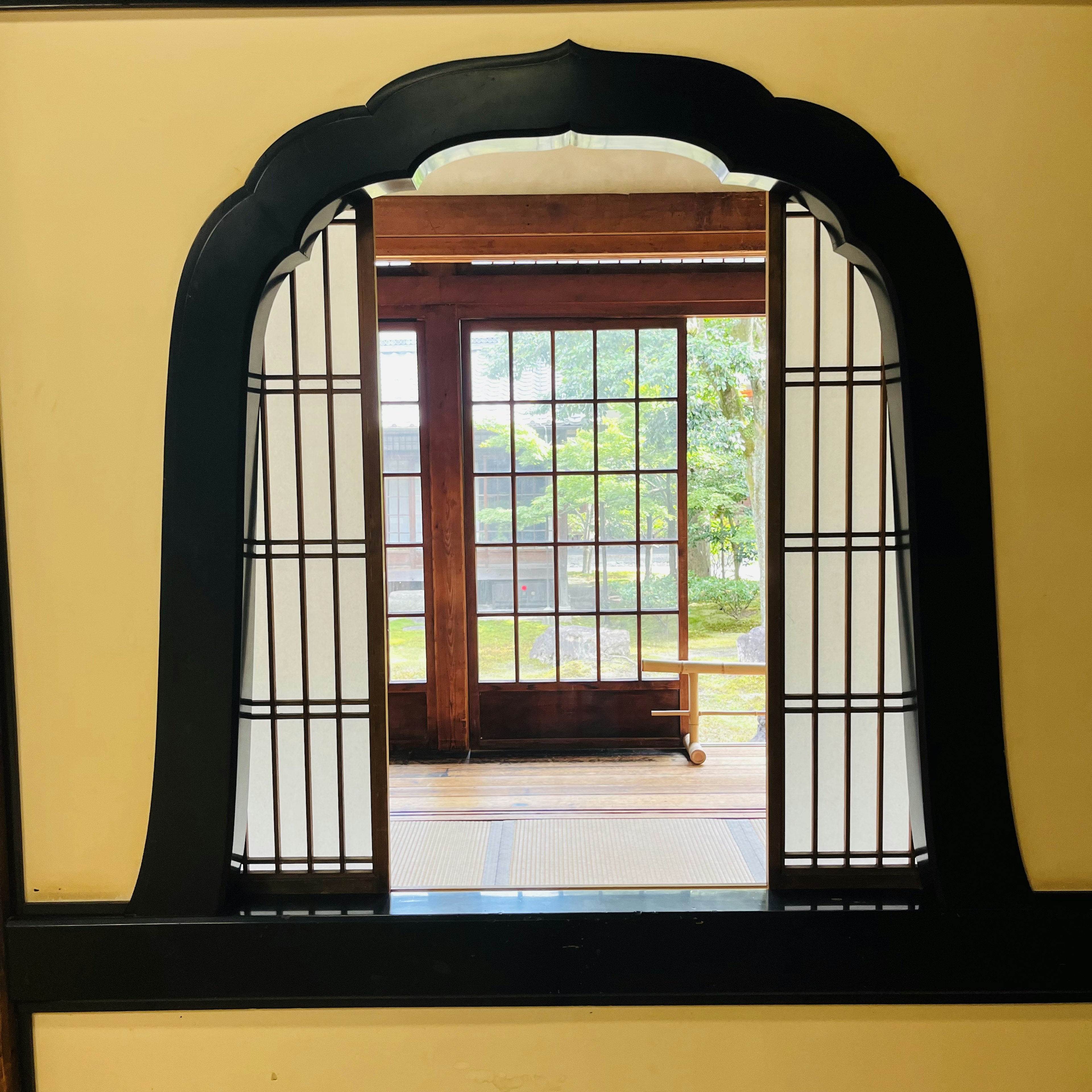 View of a garden through a traditional Japanese window frame