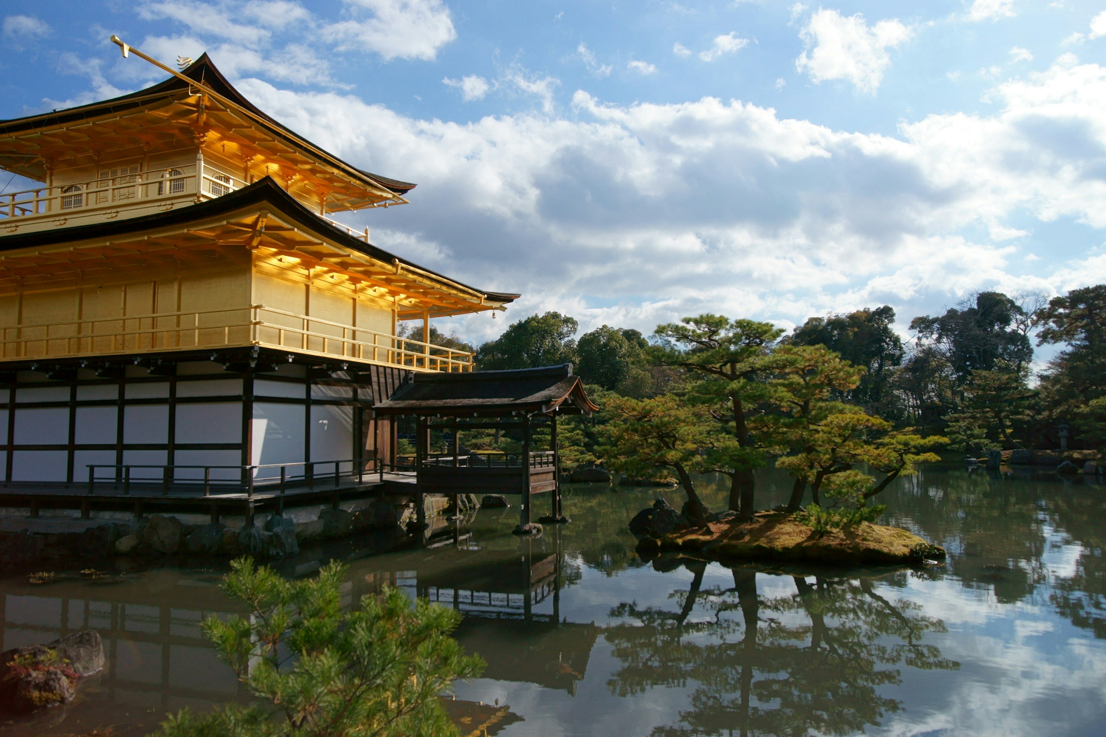 Pemandangan indah Kinkaku-ji yang memantul di air dengan struktur emas dan pohon hijau