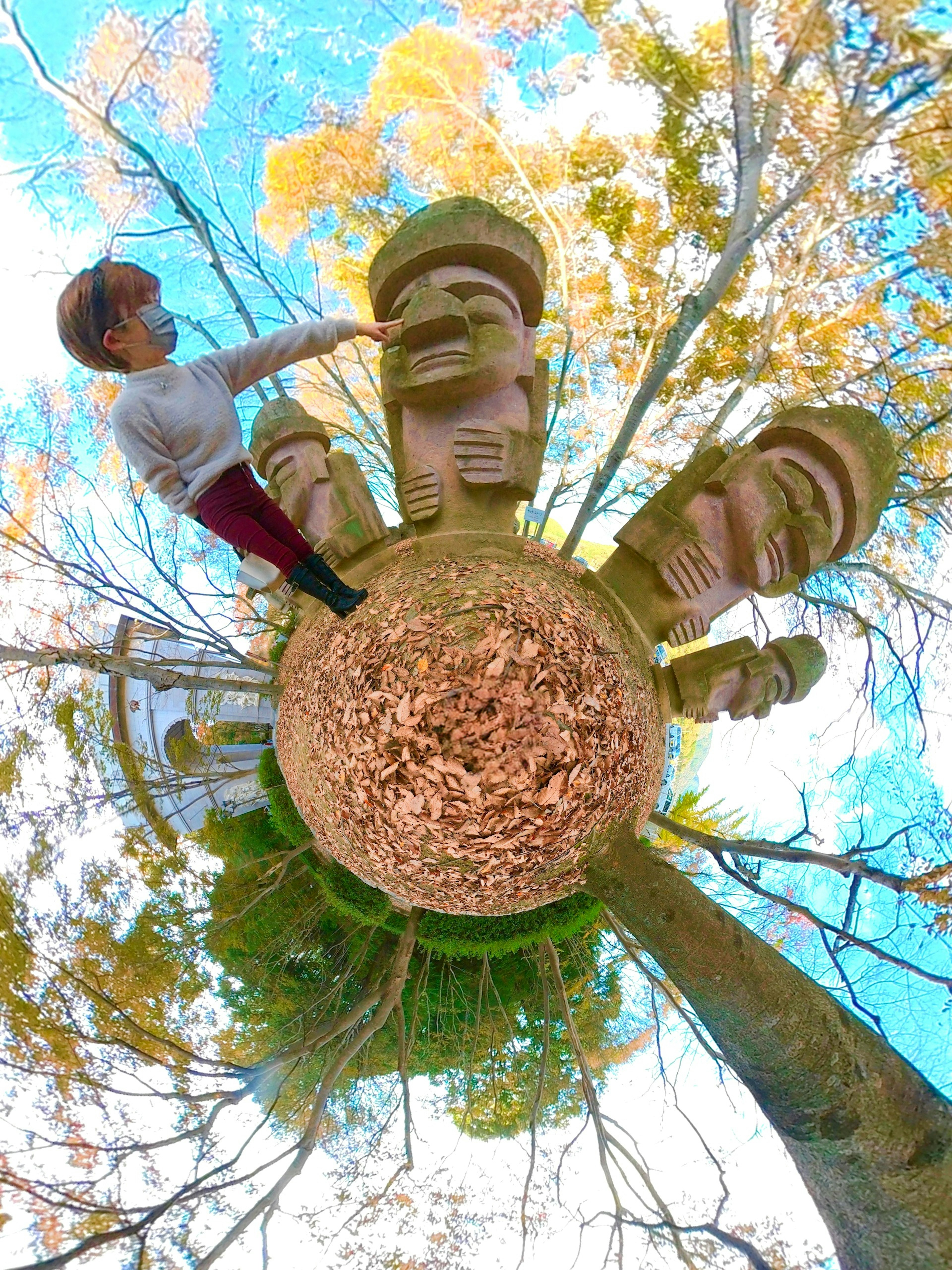 Mujer interactuando con estatuas Moai entre árboles de otoño