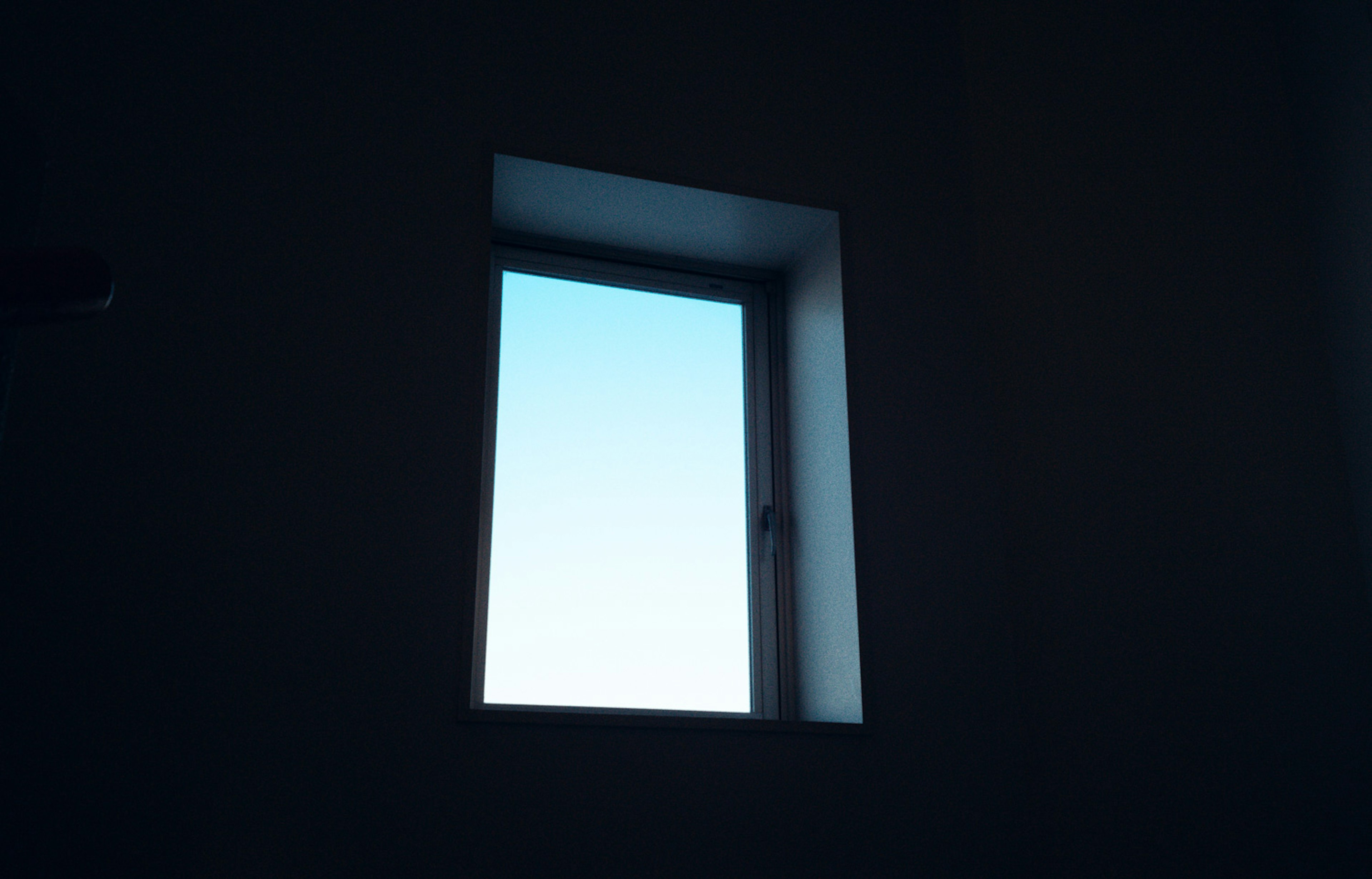 A window in a dark room showing a clear blue sky