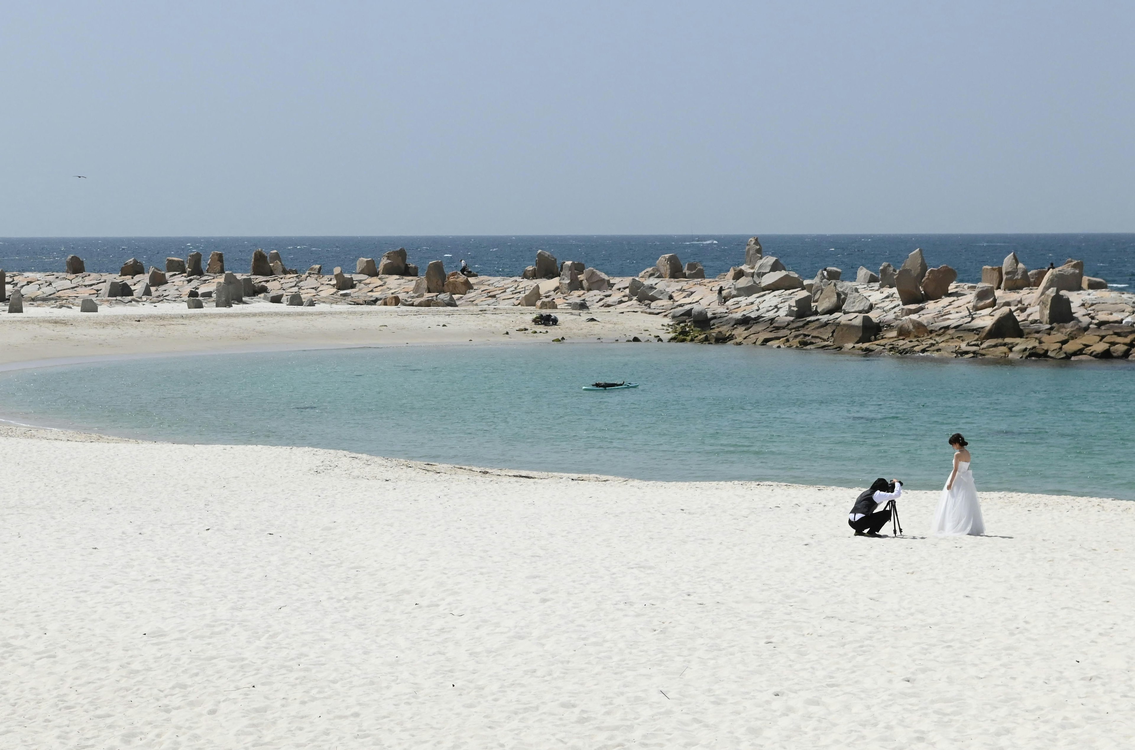 Una pareja tomando fotos de boda en una playa de arena blanca cerca del océano