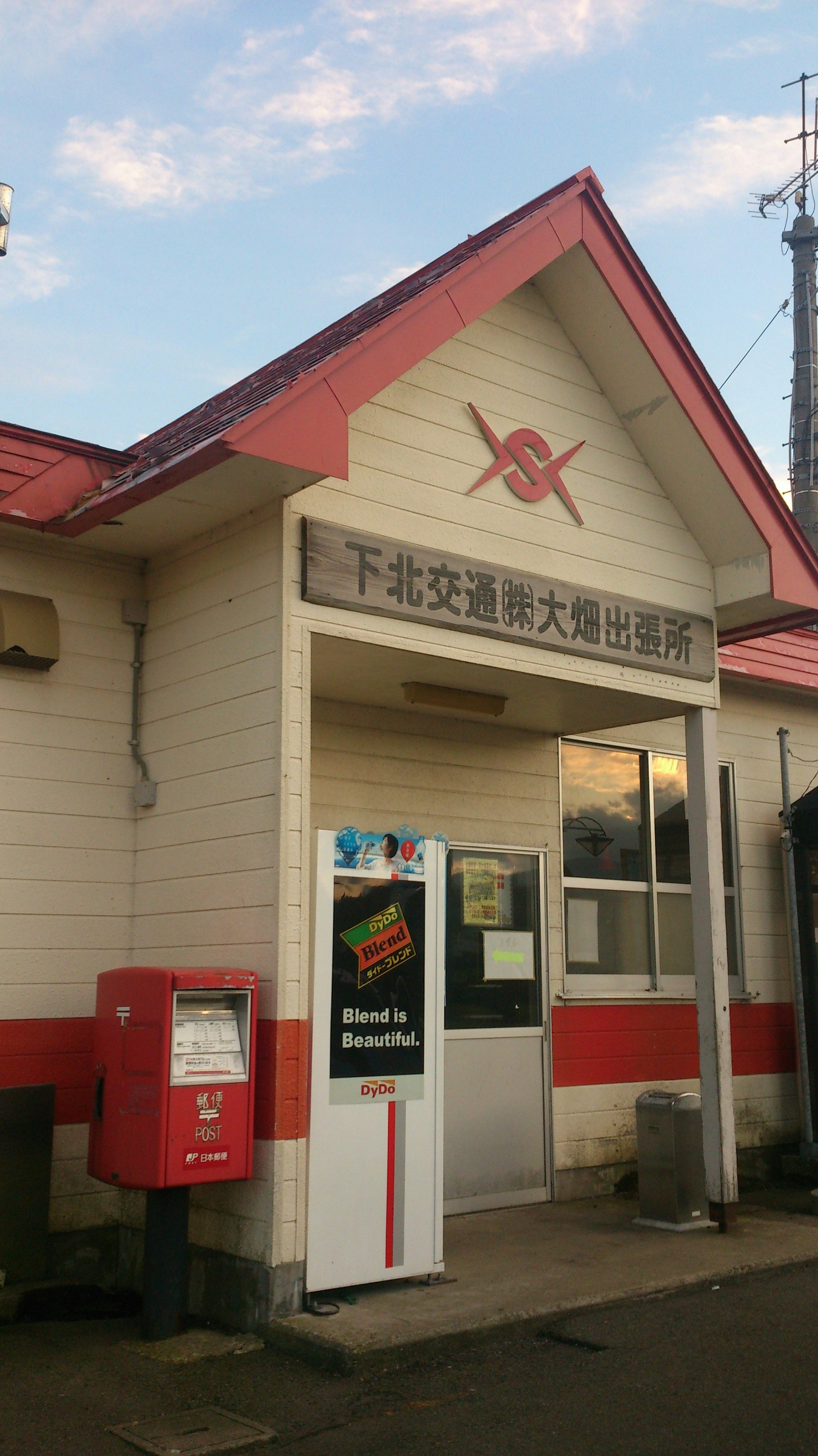 Kleine Bahnhofsgebäude mit rotem Dach und Briefkasten