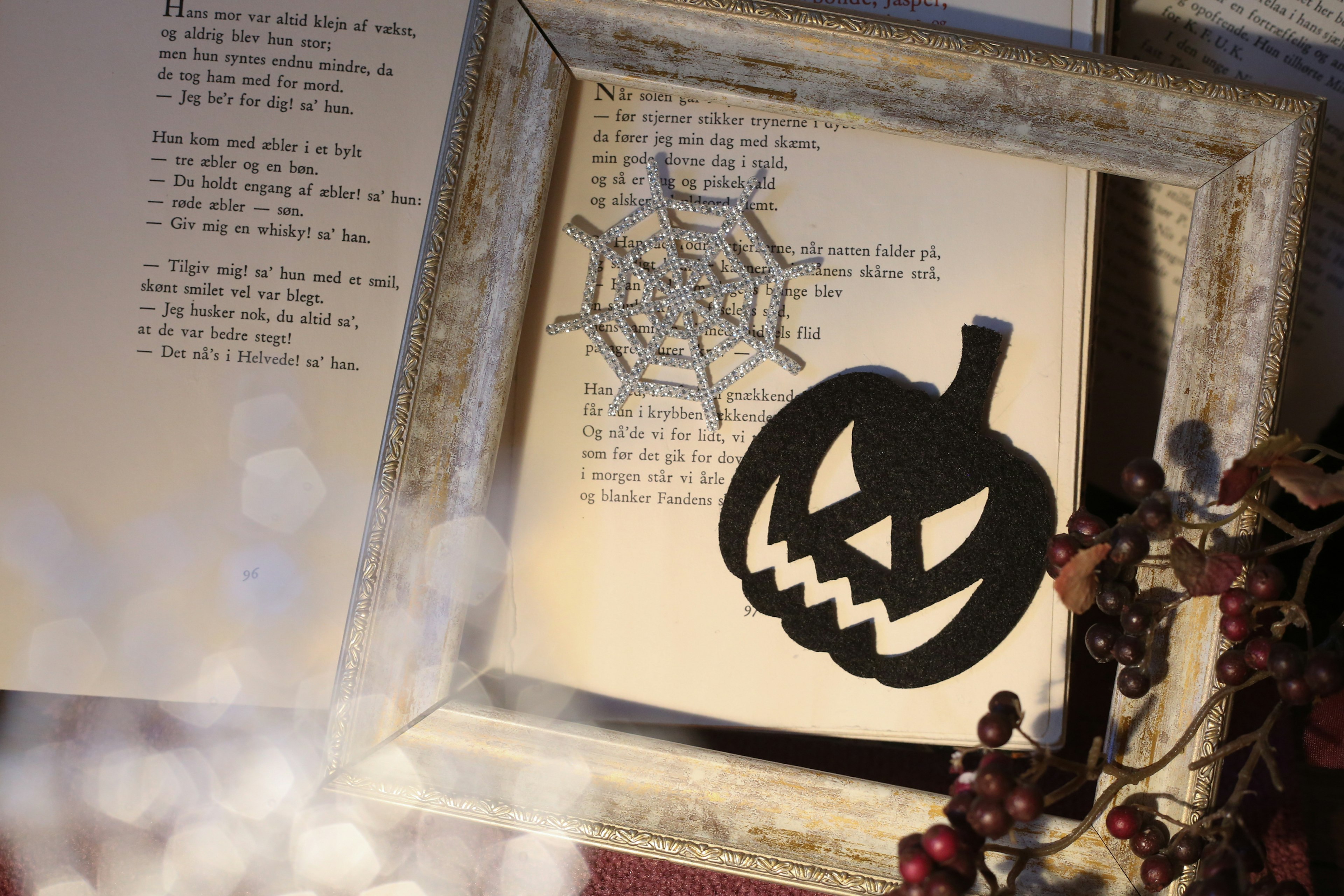 A Halloween-themed frame with a pumpkin and spider web on a book page