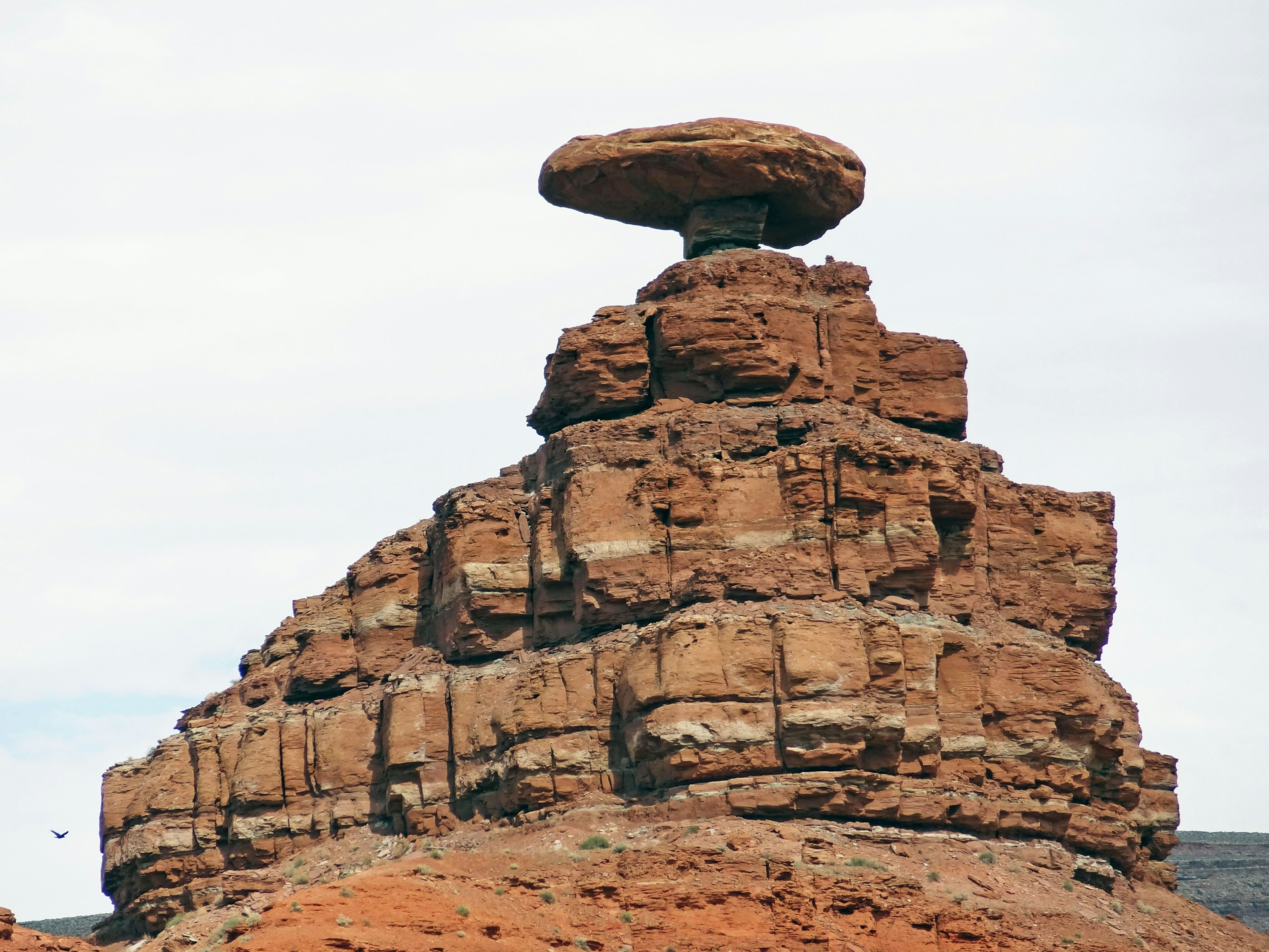 Una formación rocosa única con una gran piedra en forma de mesa sobre capas de rocas rojas