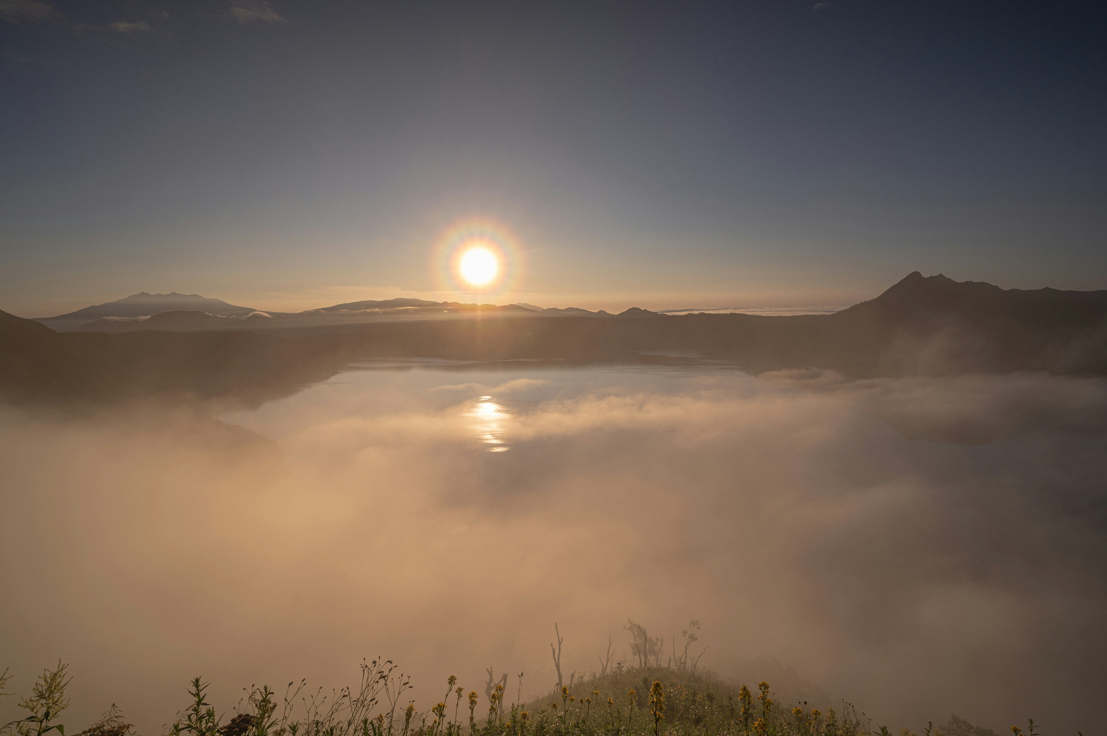 霧に包まれた湖とその上に昇る太陽の美しい風景