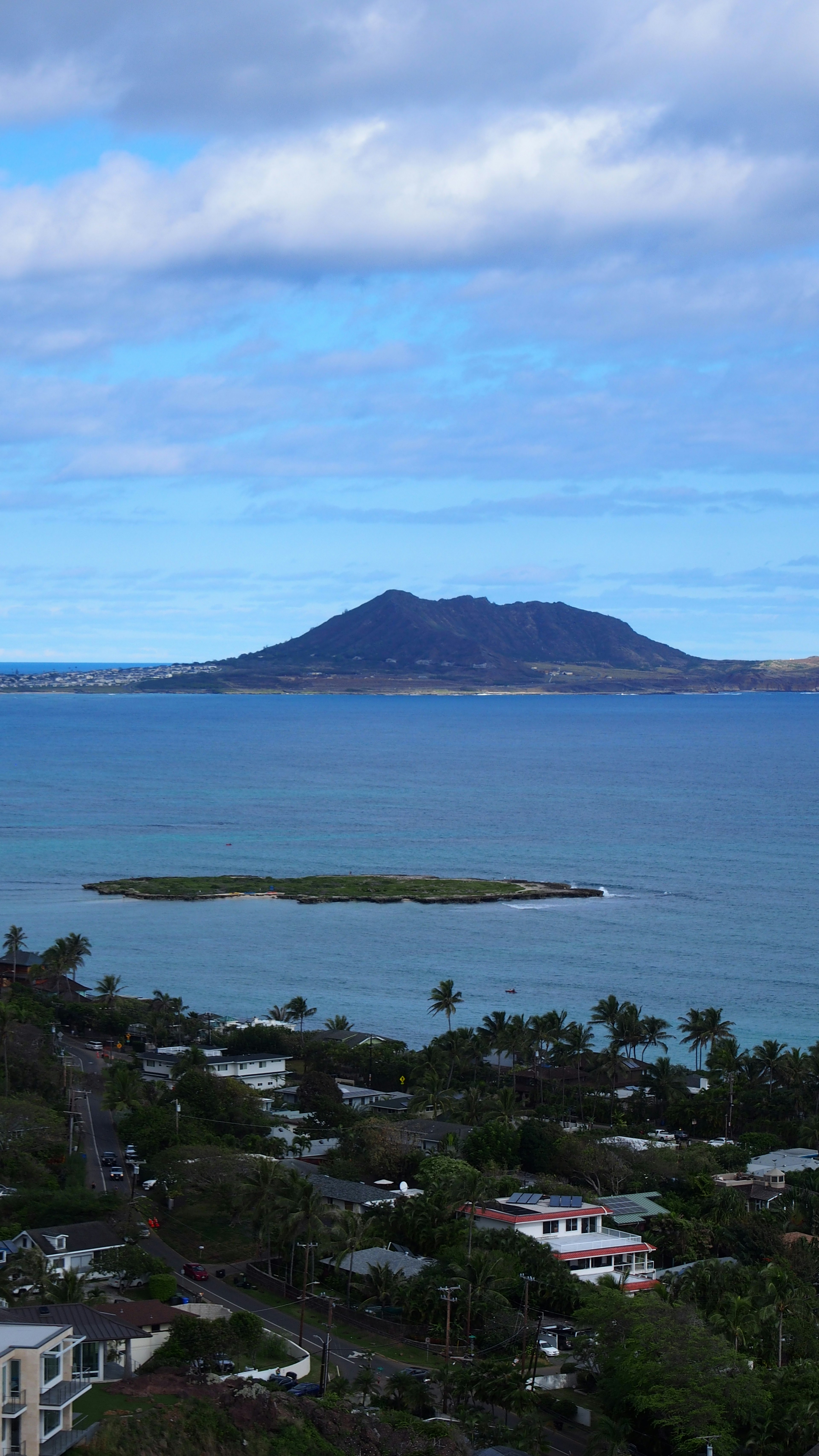 青い海と雲のある空の背景に小さな島と火山が見える風景